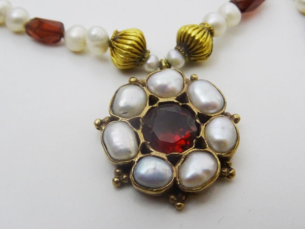 A creation of our Jerusalem workshop.
Pearls , Garnets and various antique 18 karat Gold Beads form the necklace,
The center piece is made in 9 karat gold and is made in our workshop. Set with a Beautiful 8 mm Round Garnet and wonky shaped Biwa