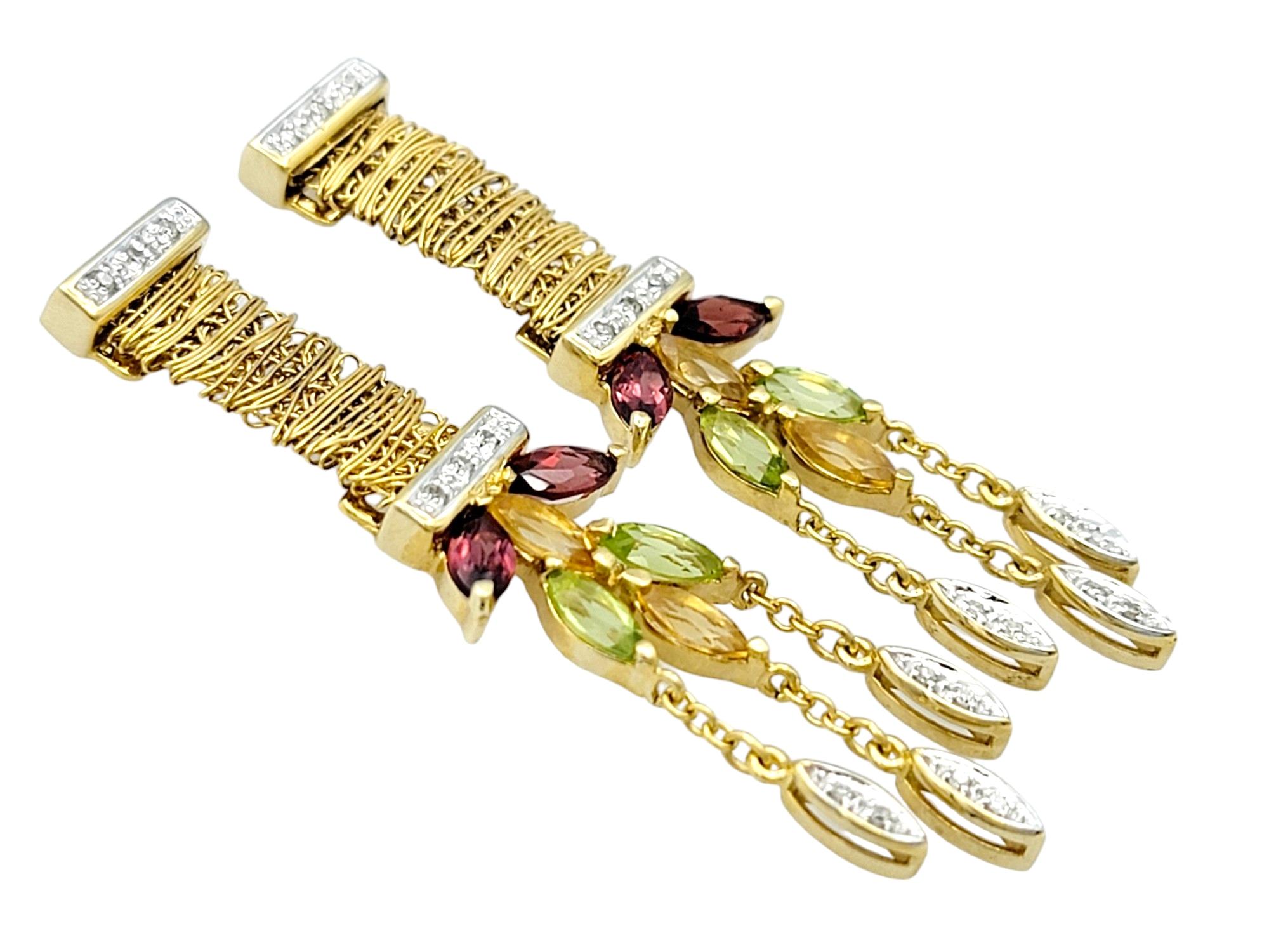 This breathtaking pair of multi-gemstone earrings, set in radiant 14 karat yellow gold, is a vibrant and enchanting creation. The unique wrapped gold design, adorned with rows of diamonds on either side, adds a touch of sophistication and brilliance