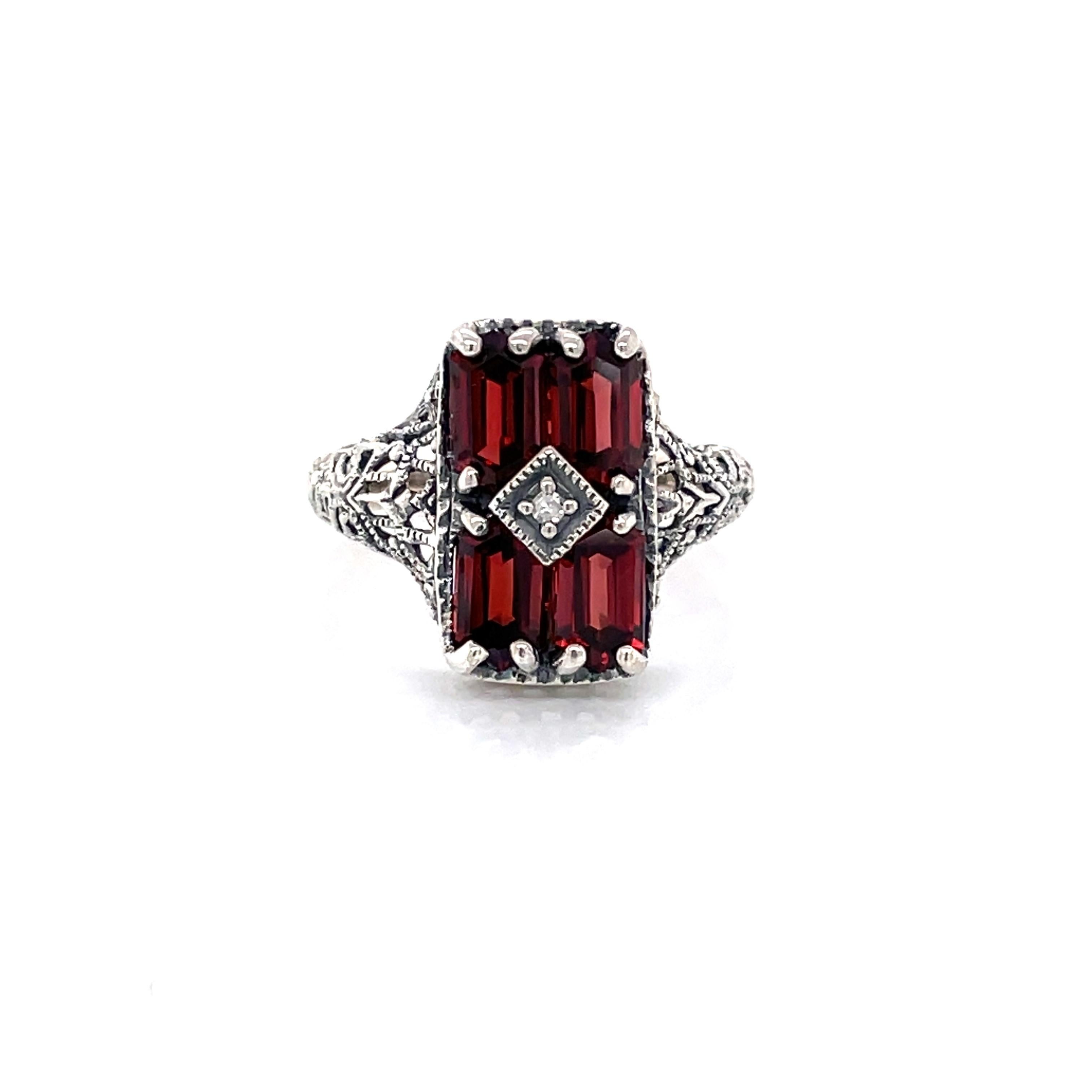 Four faceted emerald-cut deep red garnet stones grace the front of this antique style .925 sterling silver ring. 
In size 6. New and presented in miniature antique style gift box.