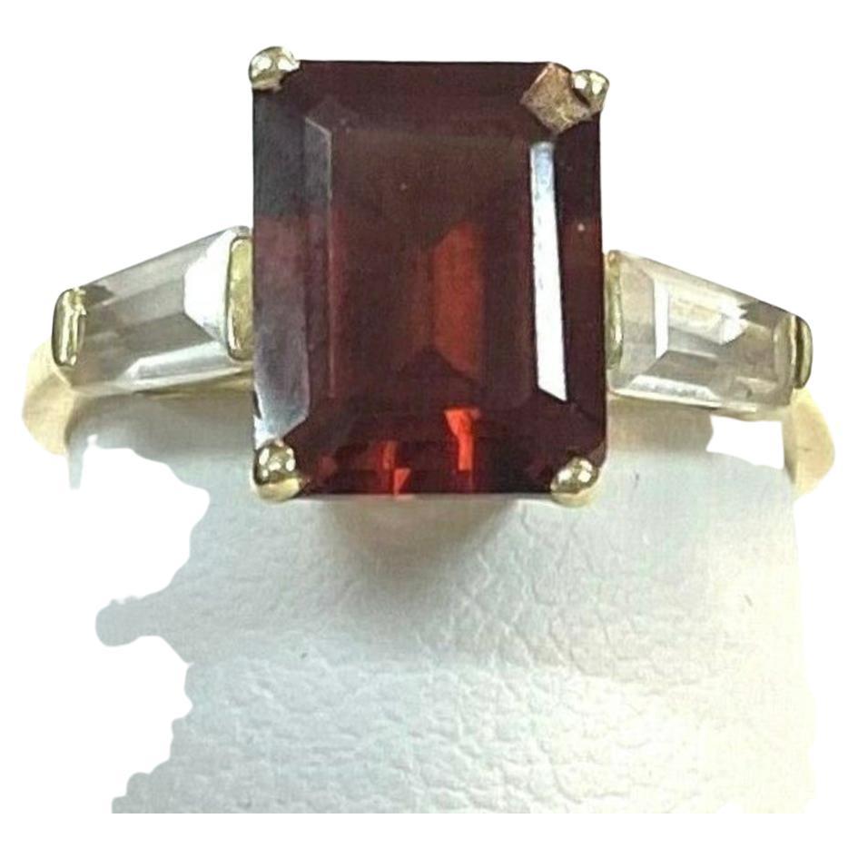 14k yellow gold emerald cut Garnet ring, 2.09 Grams TW. The dimensions of the emerald cut garnet is approximately 8.5 mm x 6 mm. Approximately 2 carats. Marked 14K. Approximate size 5.0.
