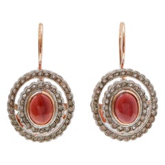 Orecchini con granati, diamanti, oro rosa e argento.