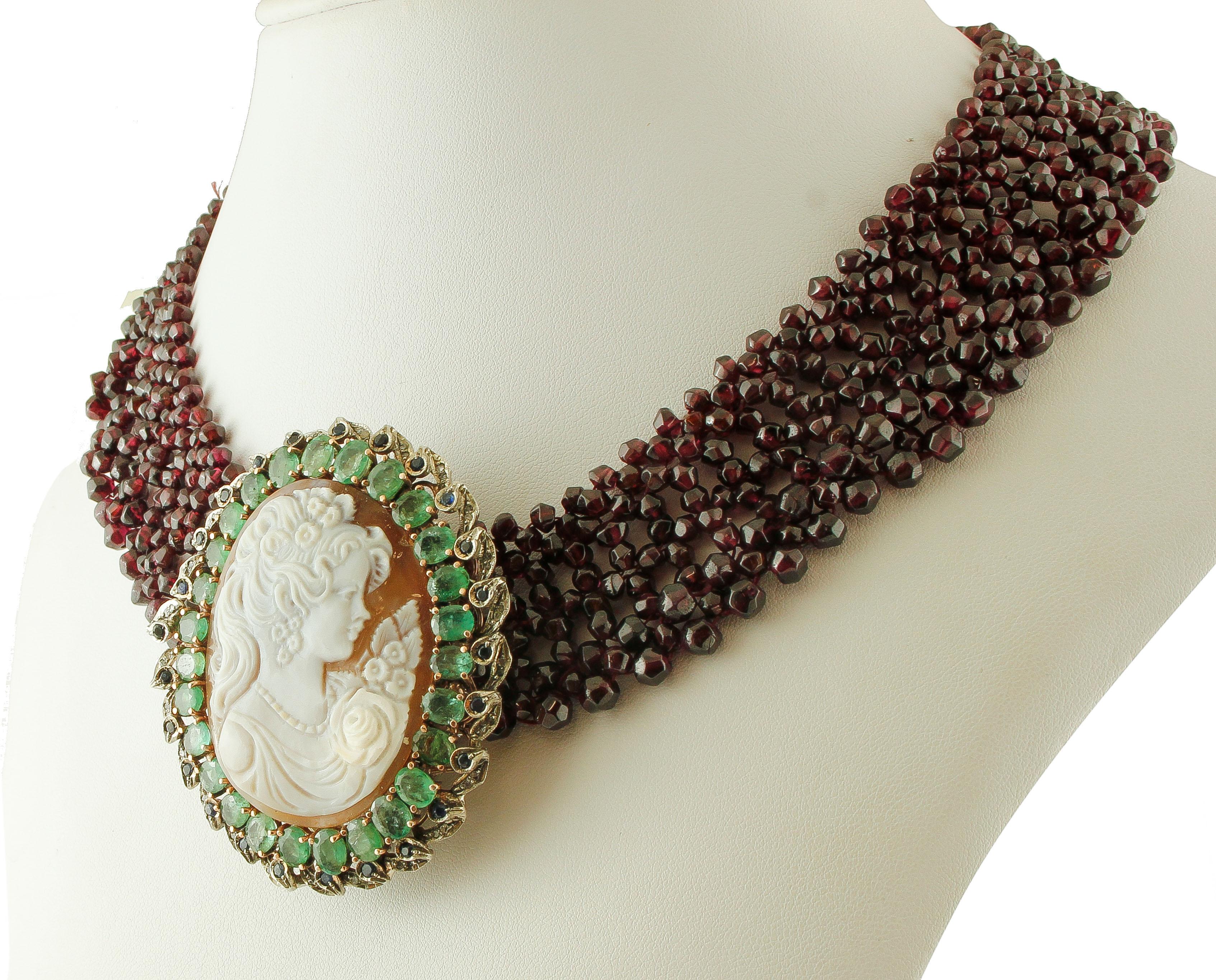 Gorgeous beaded necklace realized with 566ct of garnet beads, and a closure in 9k rose gold and silver structure, mounted with a central big cameo, surrounded by a silver frame setted with emeralds and little diamonds and blue sapphires. 
This