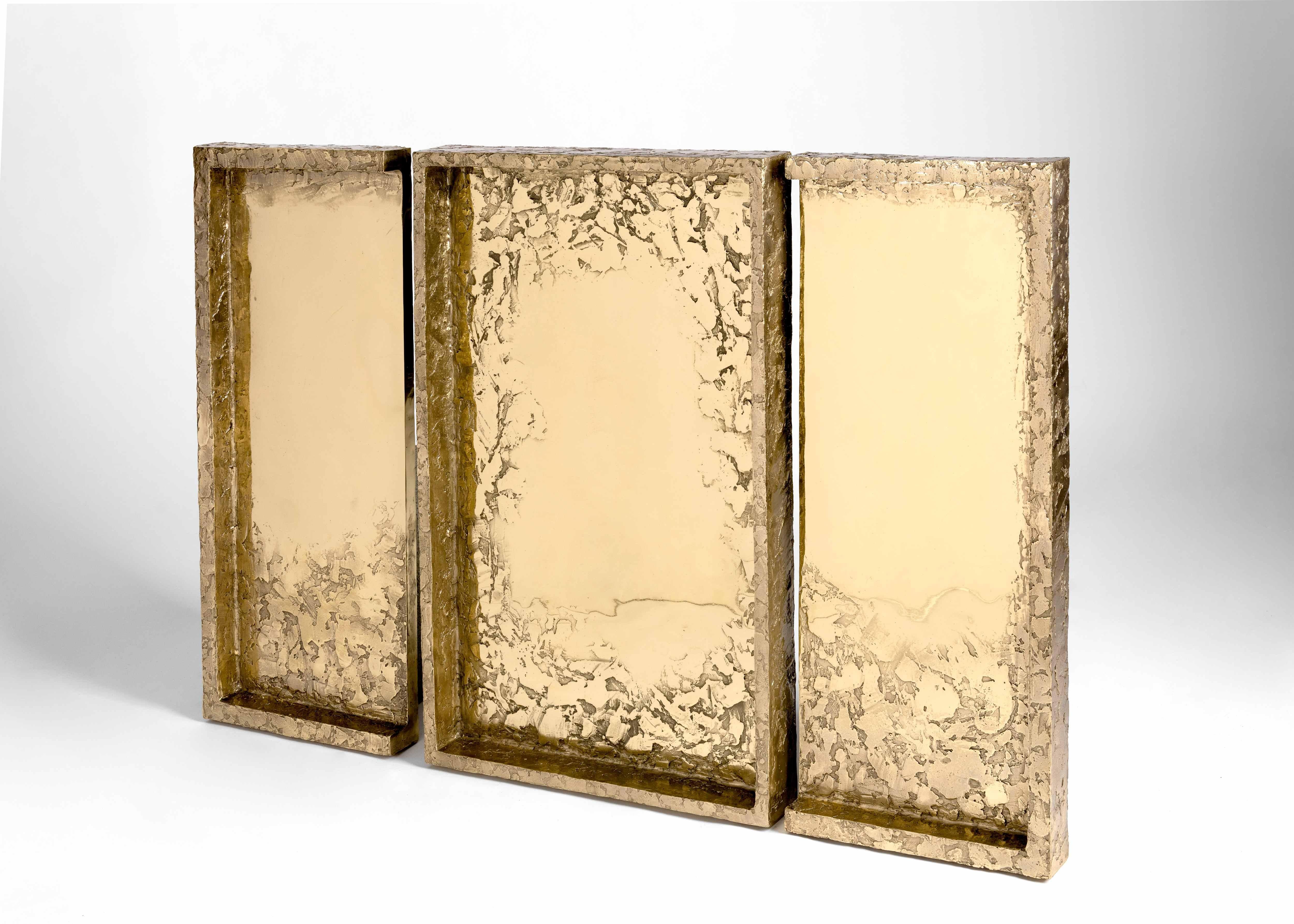 A triptych of wall-mounted sculptural mirrors composed of bronze -- highly polished at the panels' centers and rough, like baked earth, about their frames. This exquisite installation was designed and executed by the French duo Garnier & Linker,