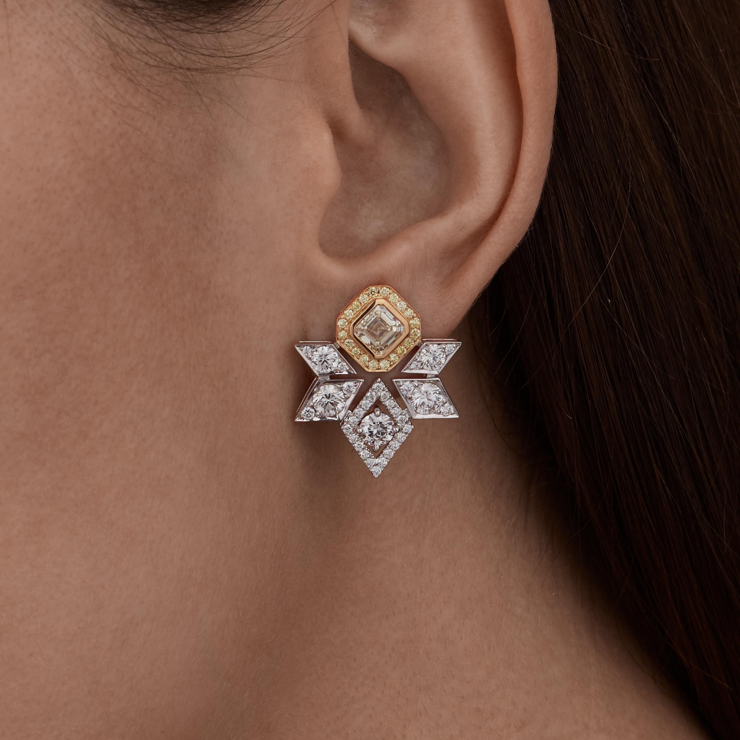 A pair of 18 karat white and yellow gold stud earrings from the House of Garrard. The earrings are set with 2 GIA Asscher cut diamonds weighing 2.02 carats, 66 round white diamonds weighing 2.61 carats and 40 round yellow diamonds weighing 0.30