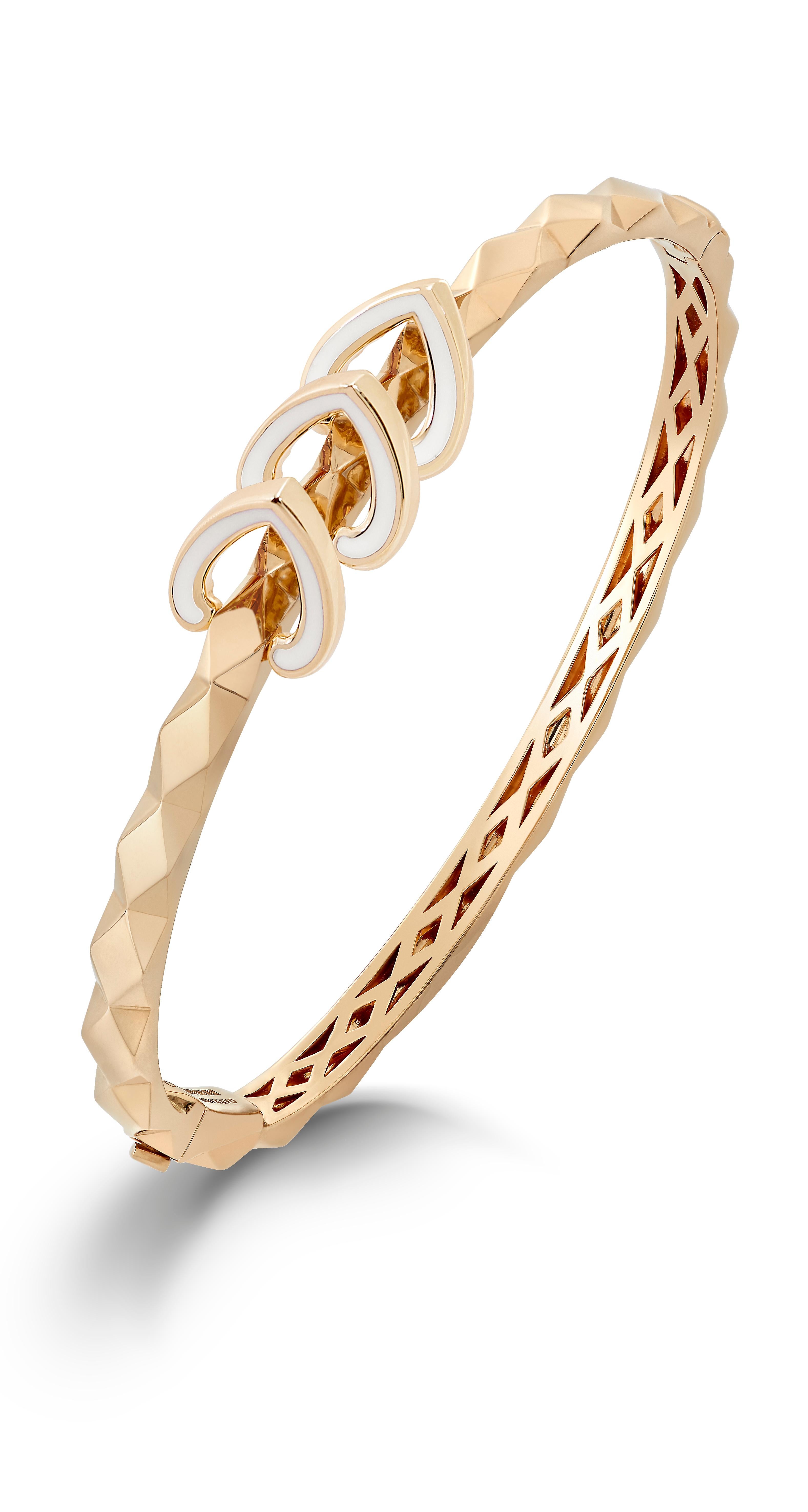 A House of Garrard 18 karat yellow gold bangle from the 'Aloria' collection, patterned with faceted gold and centered with 3 reversible round white diamond and white enamel motifs. 

39 round white diamonds weighing: 0.68cts
Dimension: 60mm x