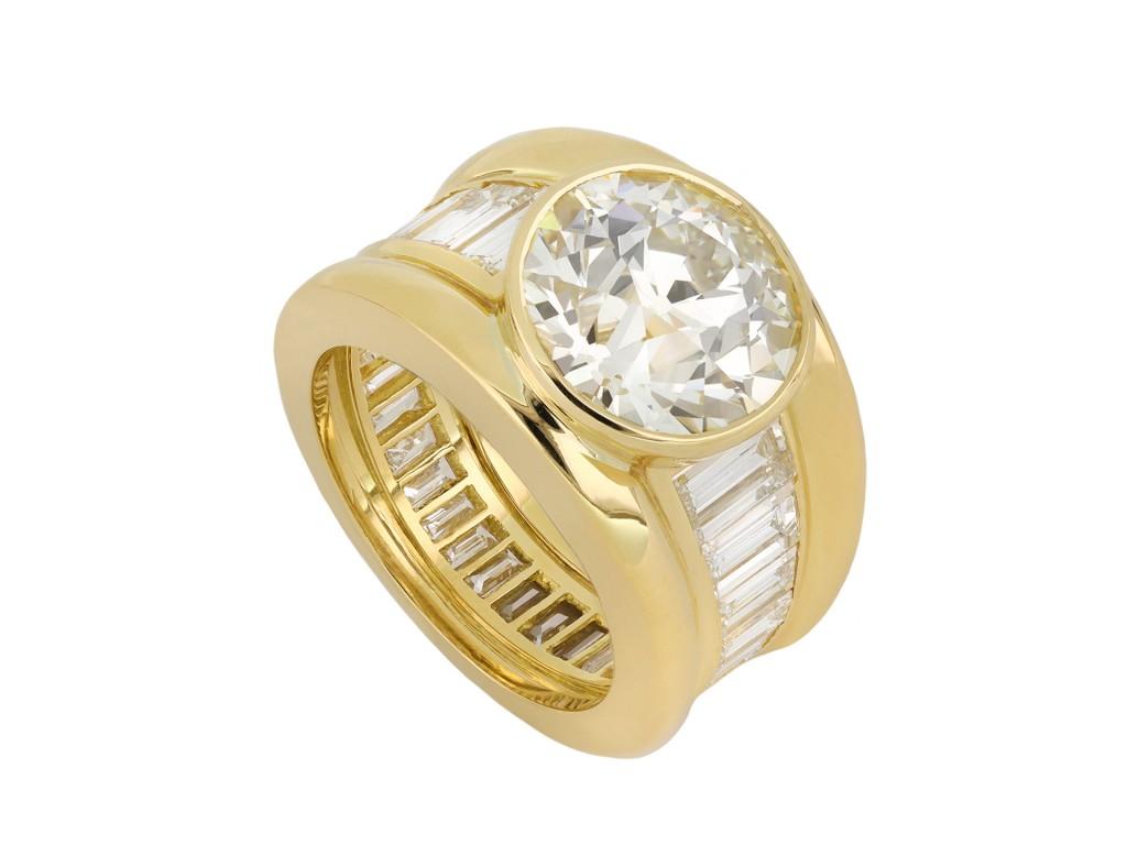 Garrard & Co. diamond ring. Set to centre with a round old cut diamond O to P colour, VS1 clarity, with a weight of 4.86 carats in an open back rubover setting, adorned further by twenty eight graduating rectangular baguette cut diamonds in open