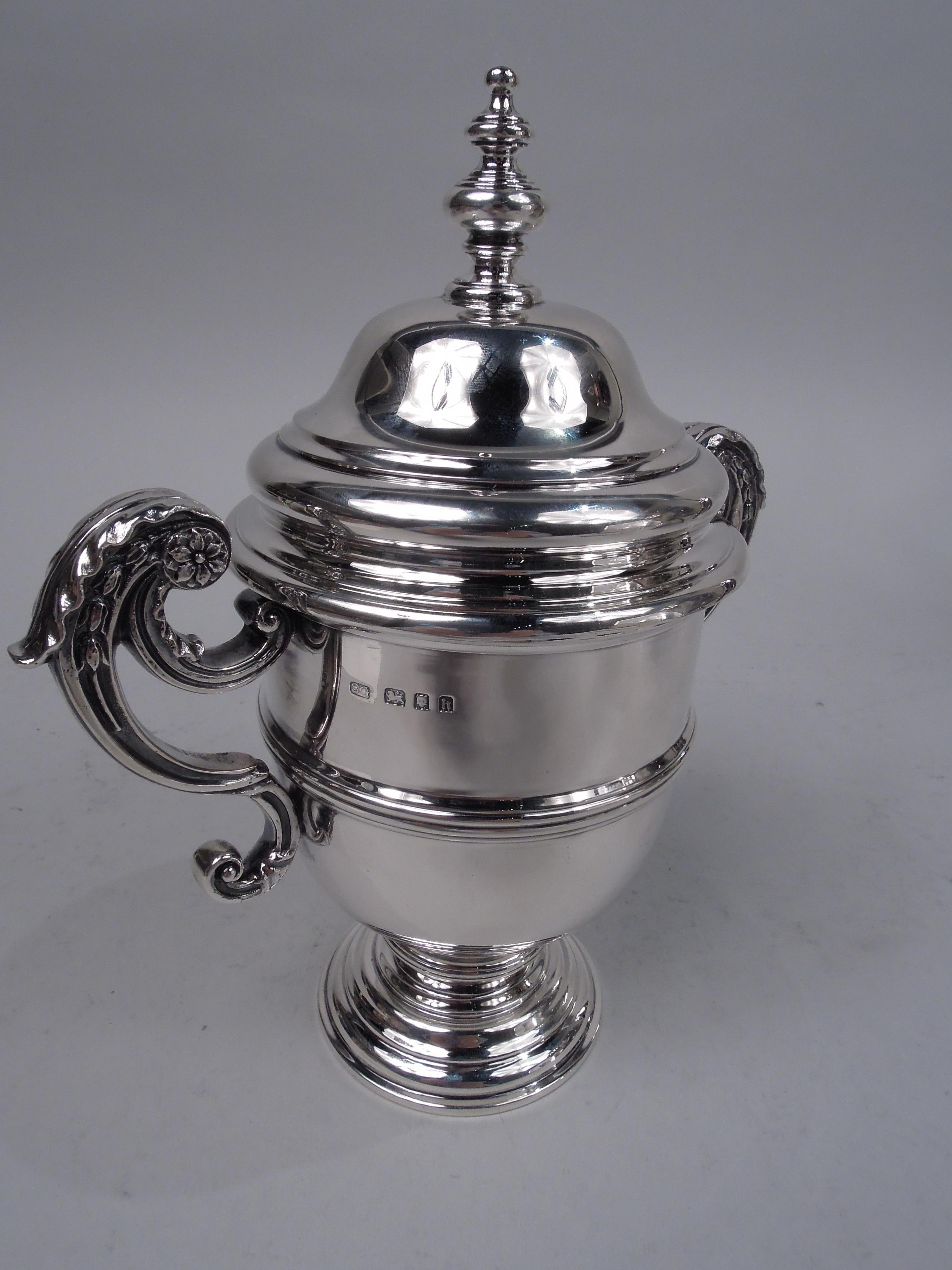 George V sterling silver trophy cup. Made by Garrard & Co. Ltd in London in 1923. Girdled urn with leaf-capped double-scroll flying side handles and knopped support; stepped and domed foot. Cover domed with vasiform finial. Fully marked. Weight: