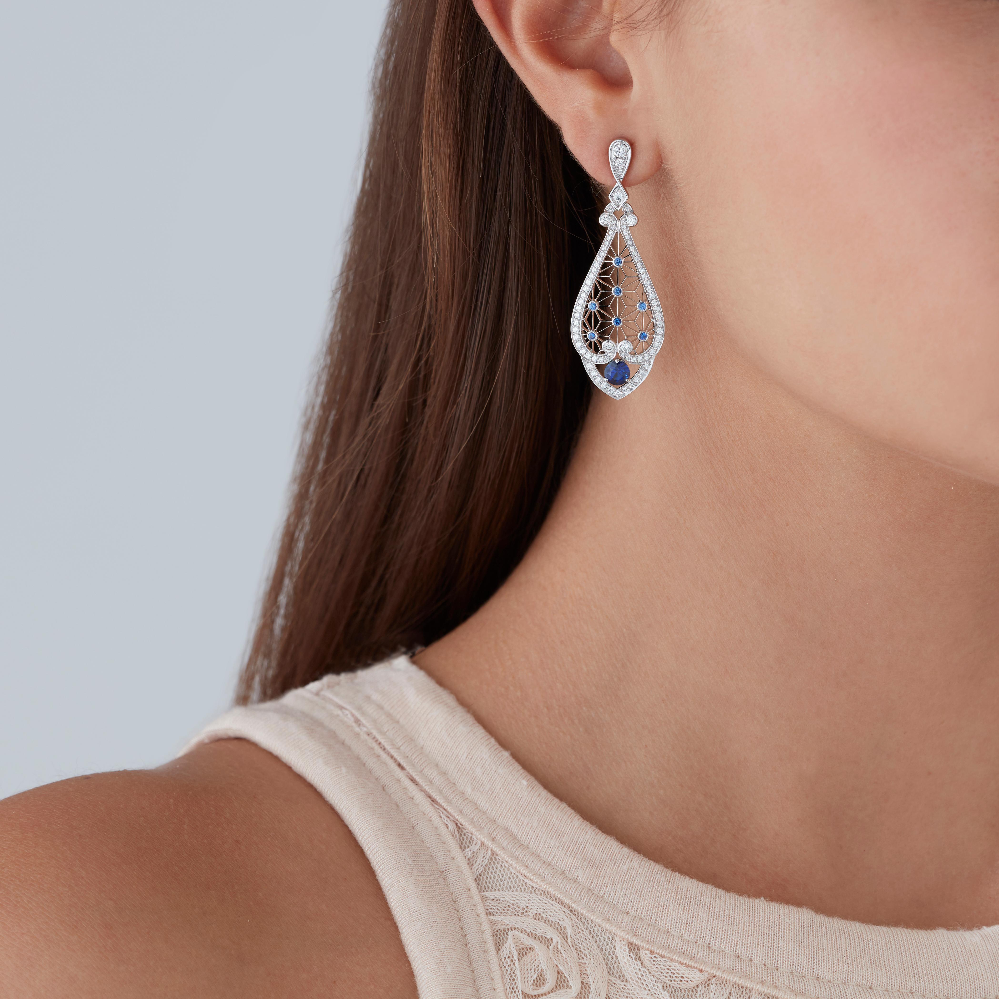 A House of Garrard pair of 18 karat white gold 'Filigree' earrings with drops from the 'Muse' collection, set with round white diamonds and round blue sapphires.         

150 round white diamonds weighing: 1.41cts
16 blue sapphires weighing: