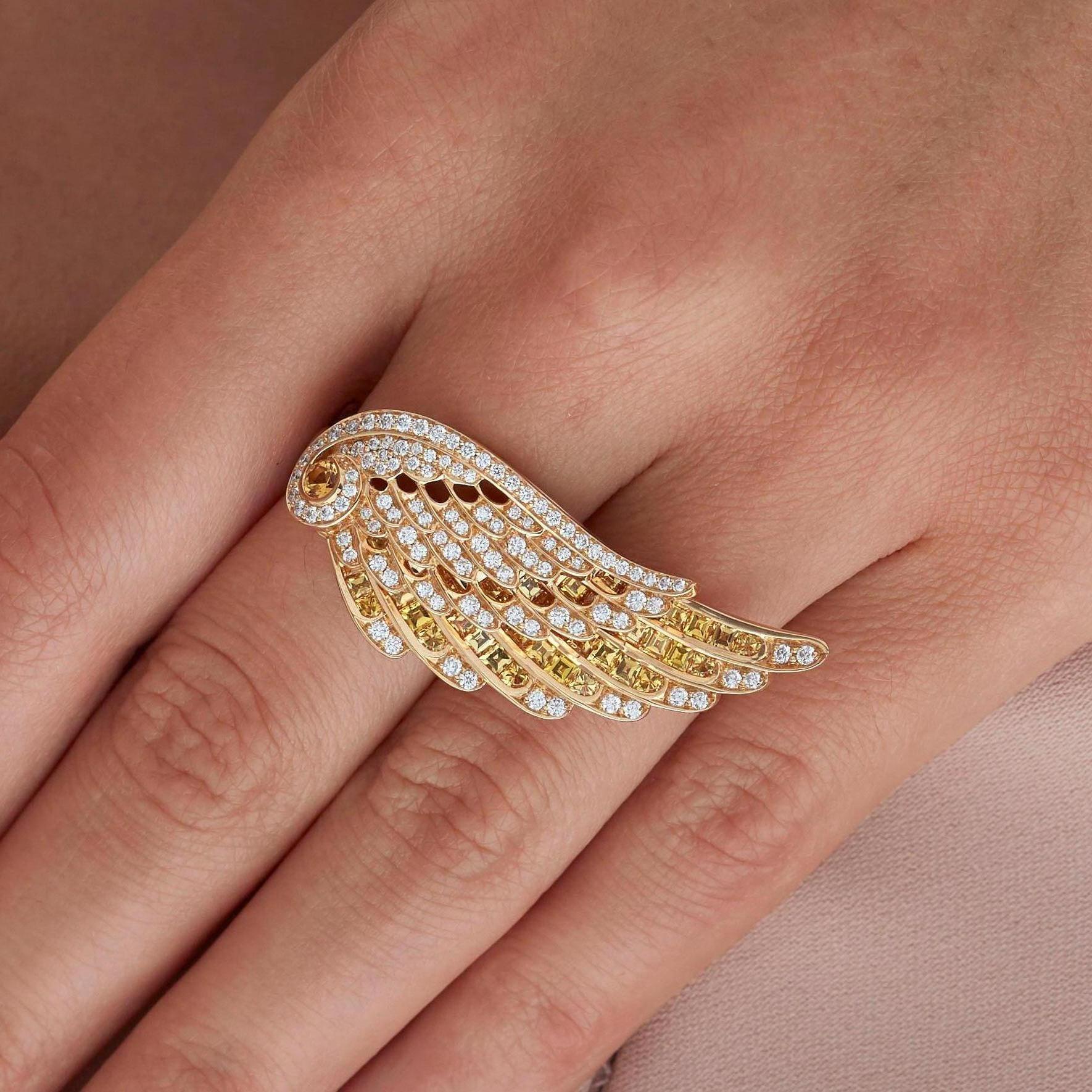 A House of Garrard 18 karat yellow gold ring from the 'Wings Embrace' collection with a cross- finger double wing motif, set with round white diamonds and round and calibre cut yellow sapphires.

106 round white diamonds weighing: 0.78cts
1 round