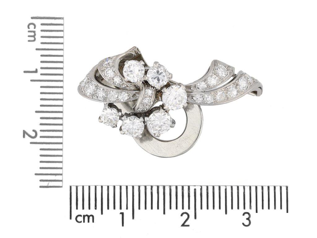 Garrards diamond clip earrings. A matching pair of earrings, each set with twenty six round old cut diamonds in open back claw and grain settings, fifty two in total with a combined approximate weight of 3.60 carats, to an openwork scrolling