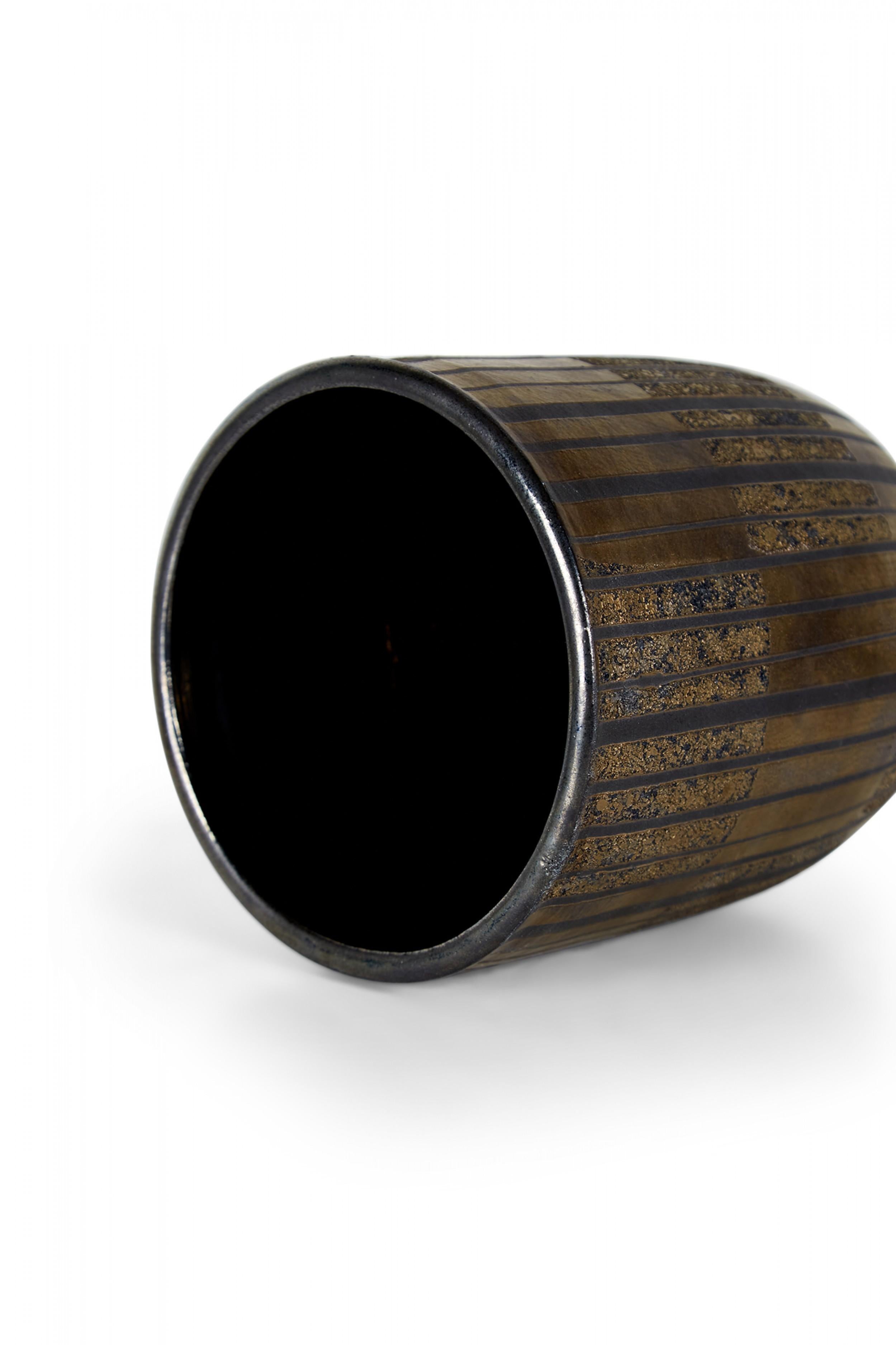 Contemporary thrown clay vase with a cylindrical form with rounded bottom and incised vertical stripes, finished with a metallic bronze and black glaze. (GARY DI PASQUALE) (Companion piece: NWL6271).
 