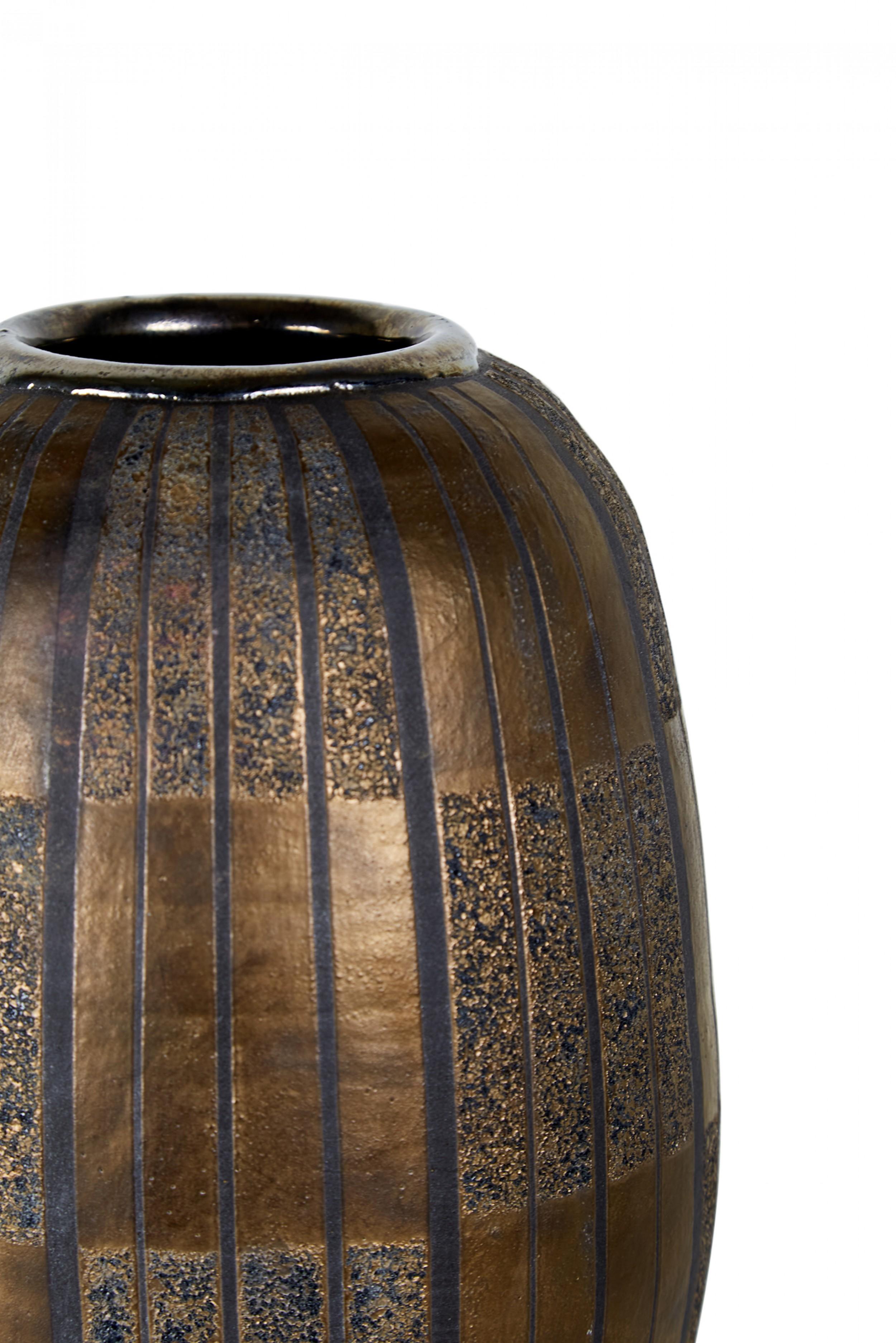Contemporary thrown clay vase with a cylindrical form with rounded top and bottom and incised vertical stripes, finished with a metallic bronze and black glaze. (GARY DI PASQUALE) (Companion piece: NWL6472).