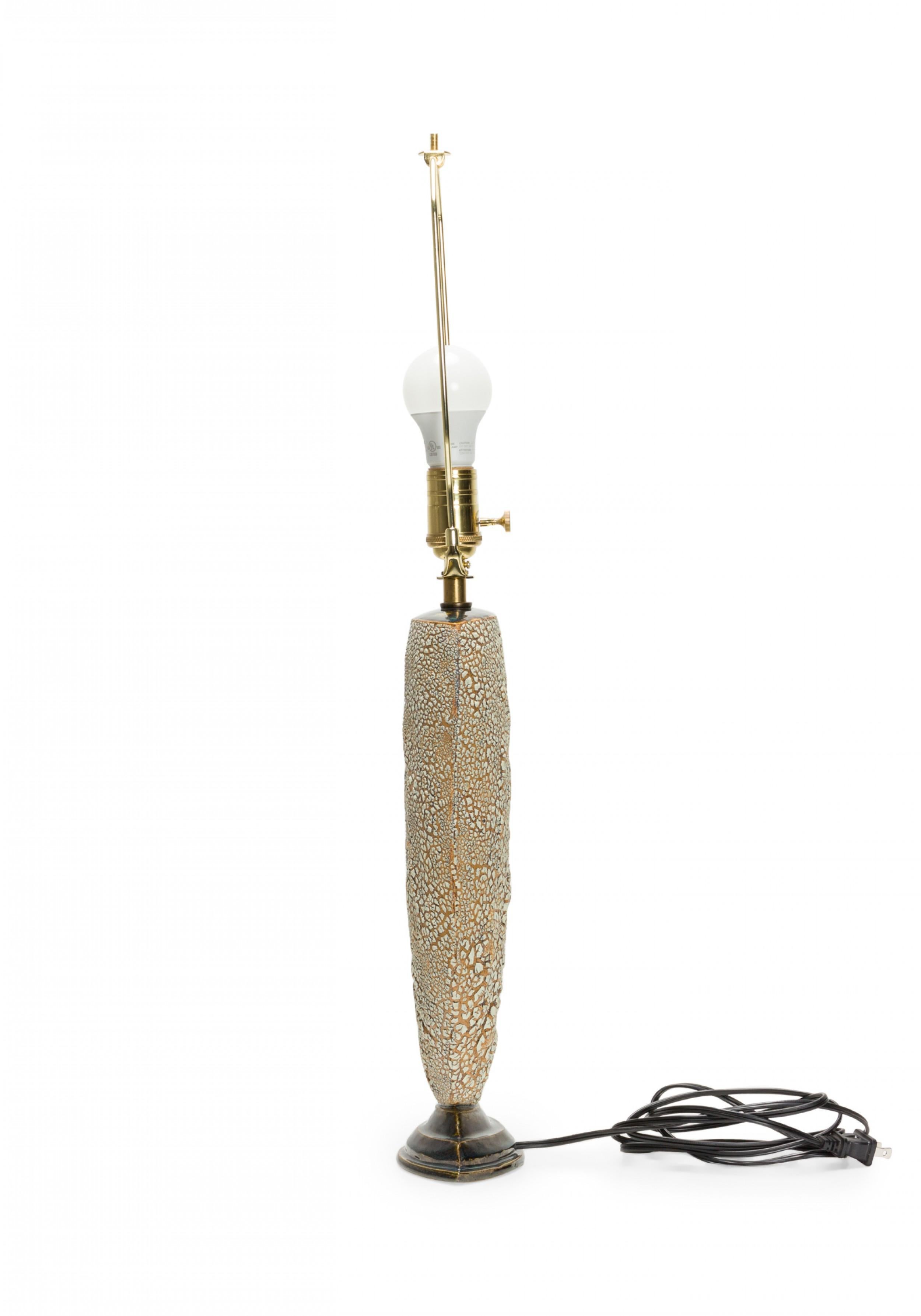 Contemporary ceramic table lamp with an envelope form and bark-like textured finish, mounted with brass hardware and topped with a light gray fabric drum shade. (GARY DIPASQUALE)

Ships with shade.