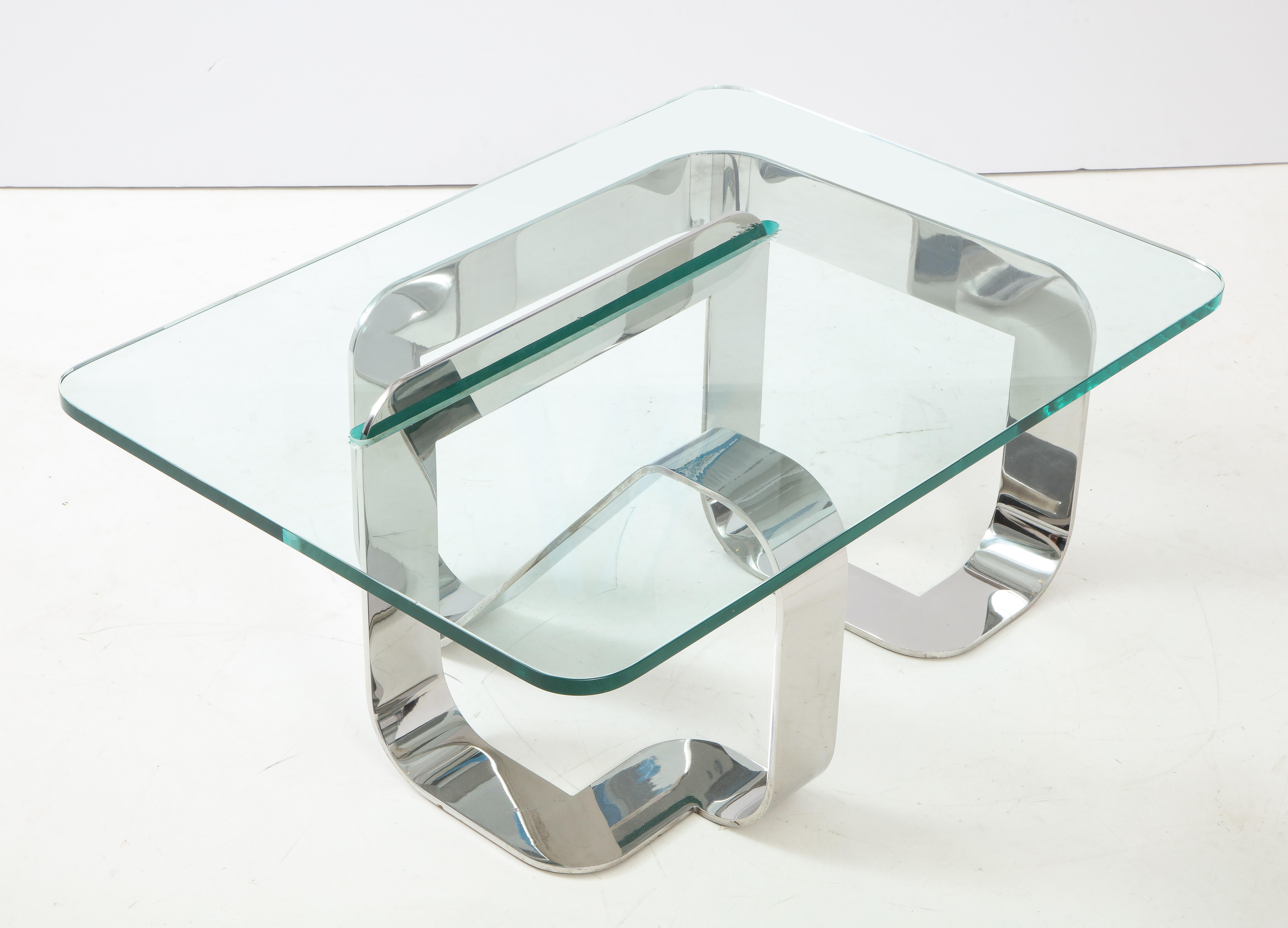 “Jason” cocktail table in stainless steel and glass by New York City designer and interior decorator Gary Gutterman. An exceptionally well-executed continuous form with the unusual feature of a segment that pierces the surface of the glass top,