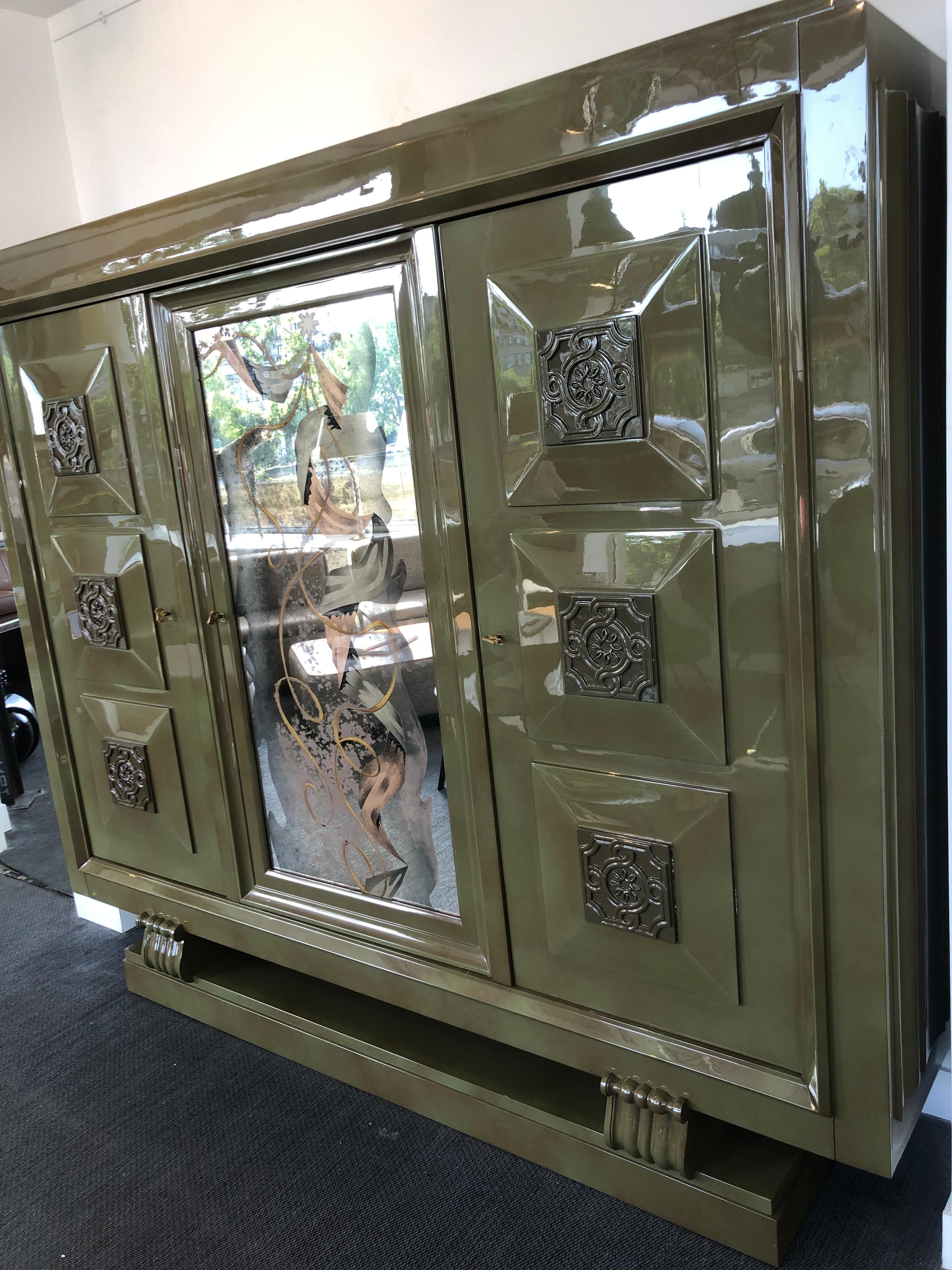 This splendid and rare large furniture piece includes three doors with engraved signed keys from the artist Gaston Poisson, “GP”. This circa 1937 cabinet is made of green lacquered* mahogany and contains 12 interior shelves (three doors each with 4