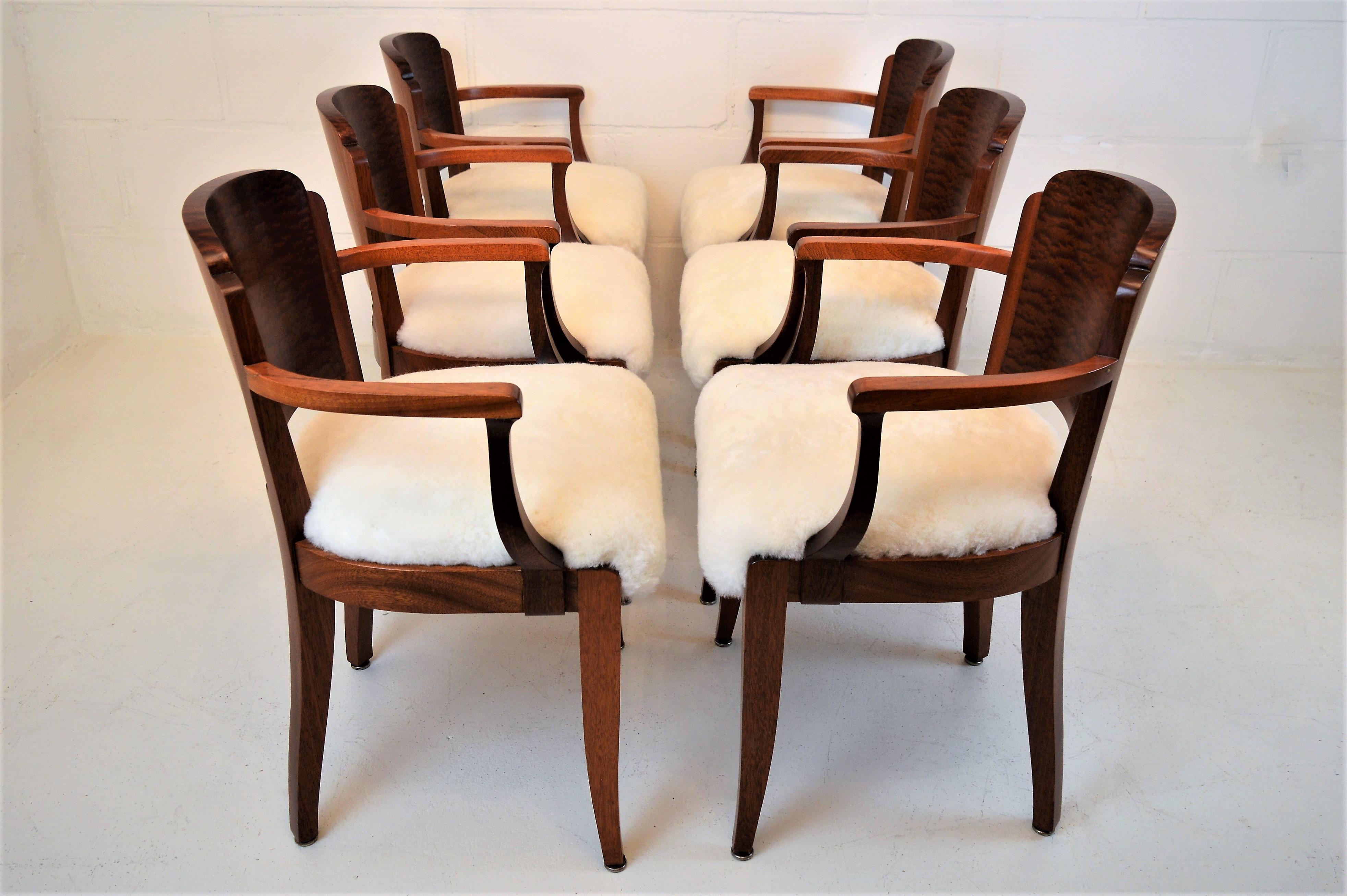 Six elegant armchairs, reupolstered with sheepskin. These solid mahogany chairs, with beautiful burl mahogany on the back-side, are created by the French designer Gaston Poisson in the early 1930s. The chairs are restored and finished in