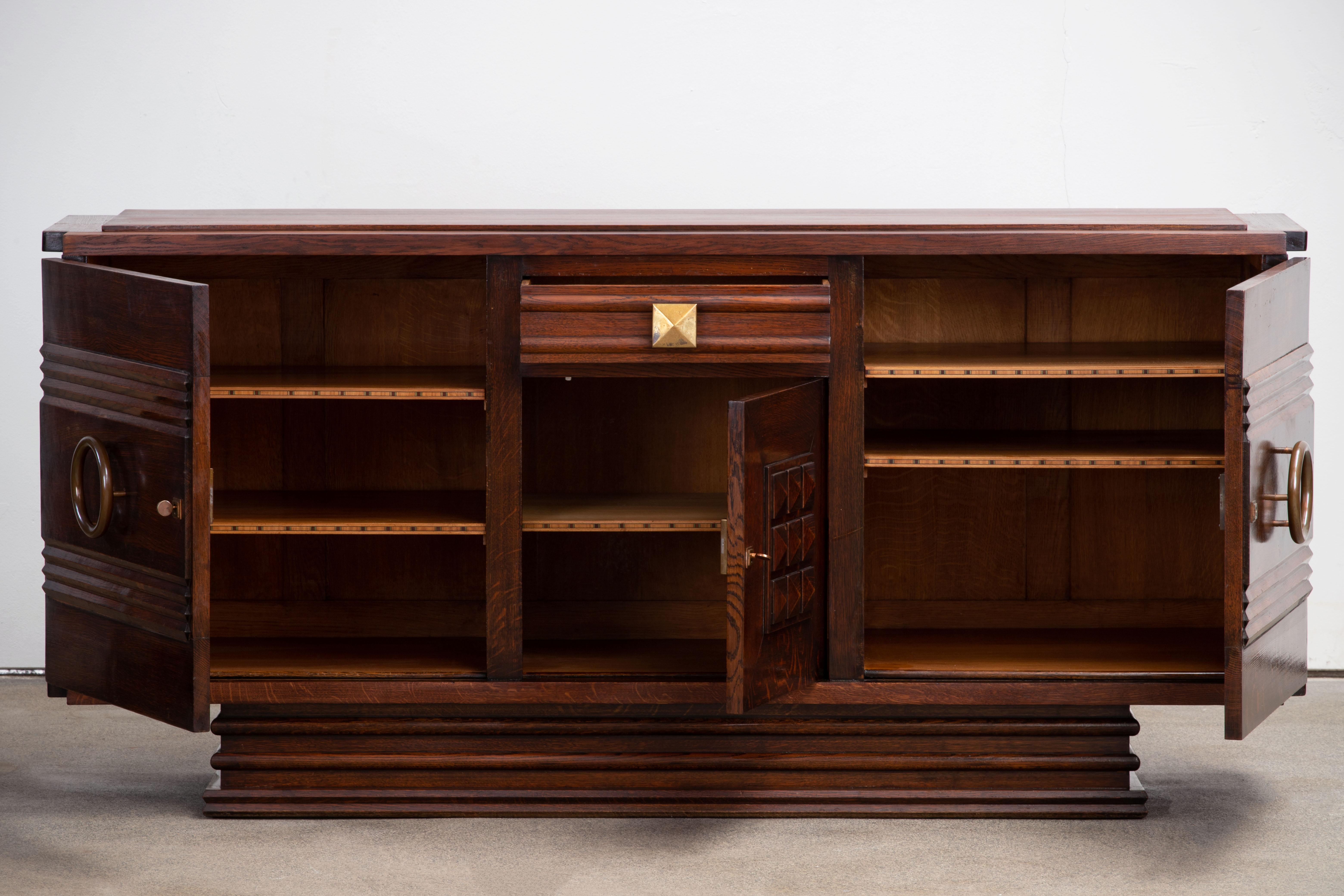 This French Brutalist Art Deco Buffet / Cabinet / Vitrine in solid oak was created in the 1940s by Gaston Poisson. 
It is in the town of Dunkirk, Normandy, France, that we had the chance to unearth this wonderful Brutalist piece.
We can clearly