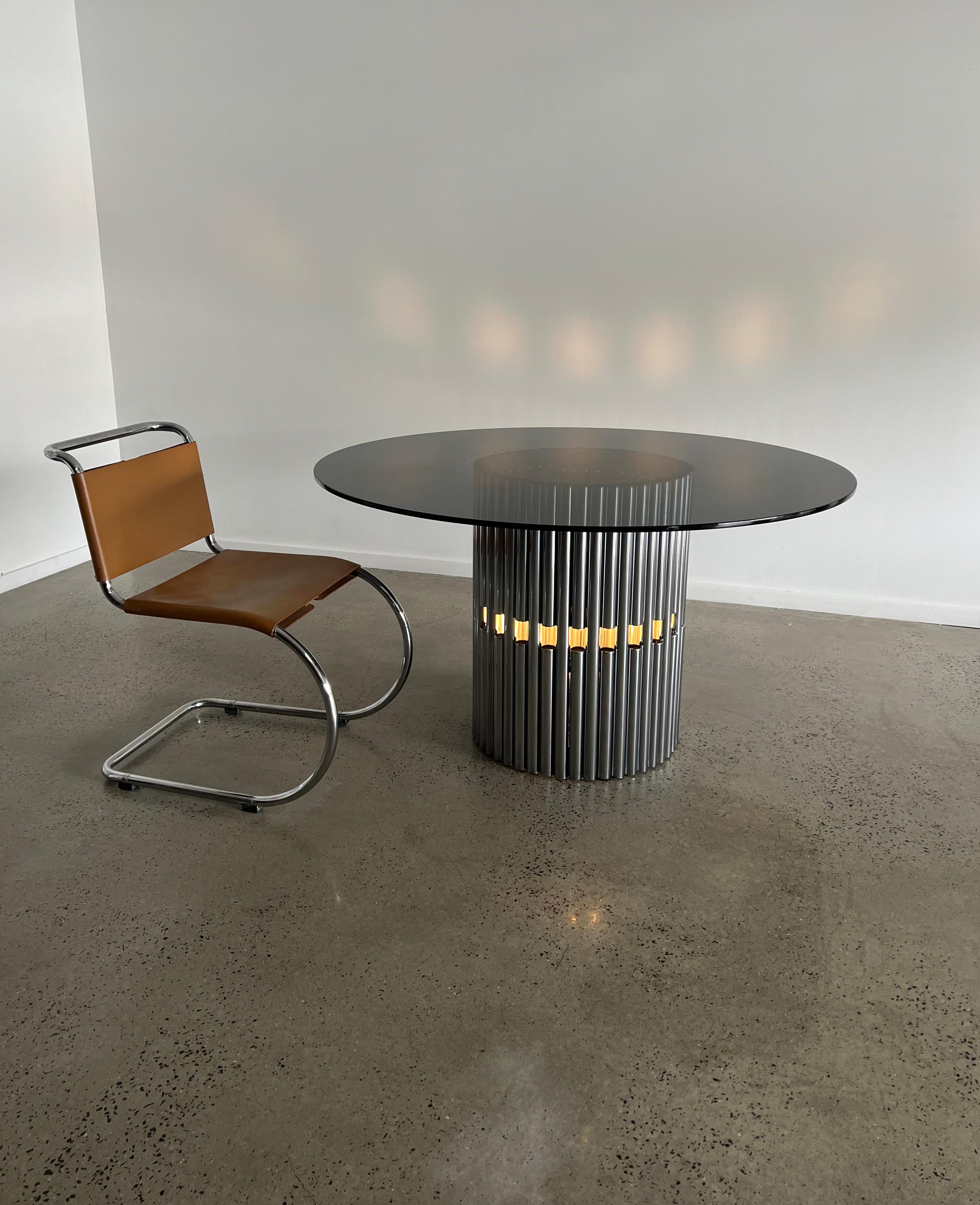 A rare chrome and smoked glass dining or centre table by the renowned Italian designer Gastone Rinaldi. A very mid century design with a silvered centre to the smoked glass top, all in excellent condition.