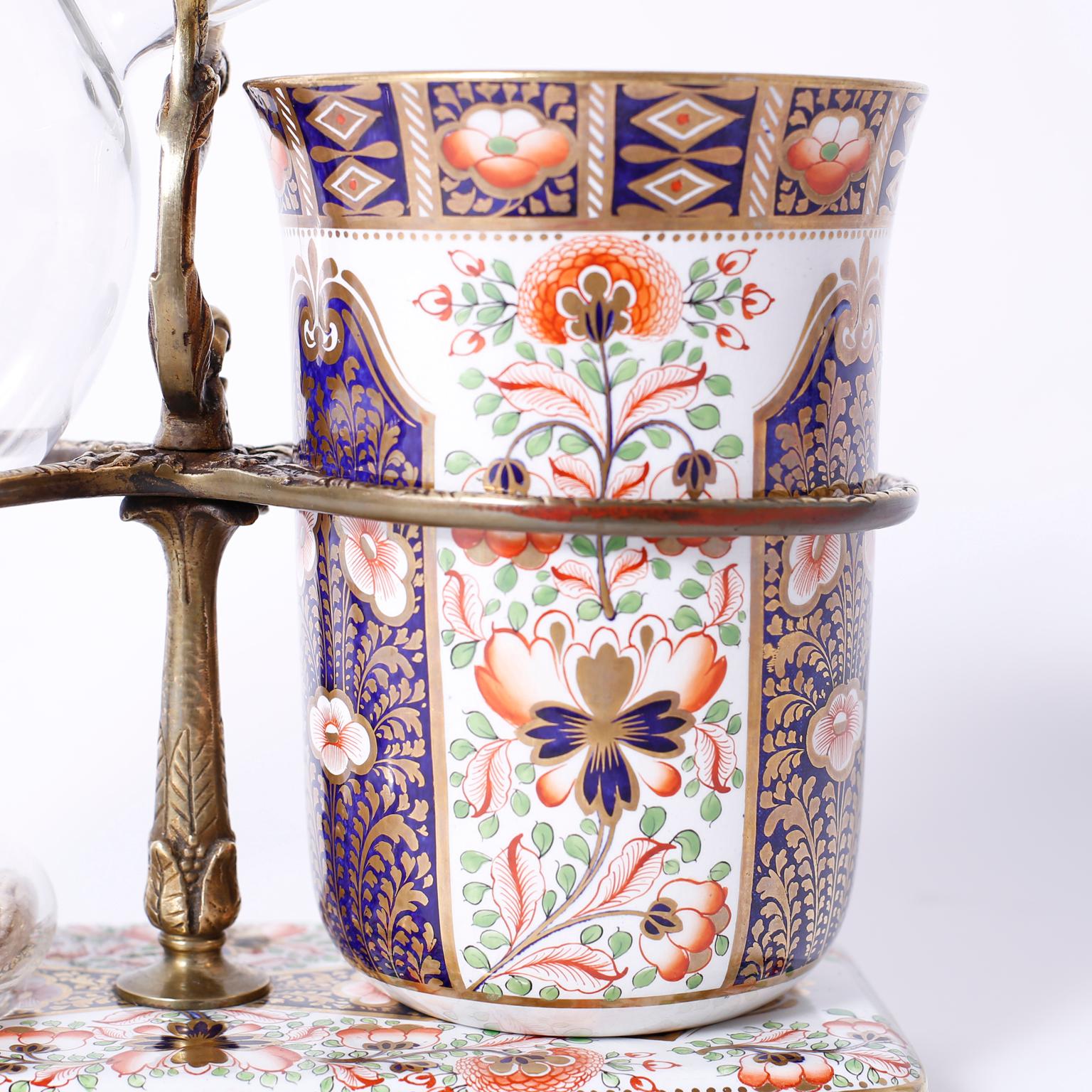 Rare and unusual Gaudy Welsh porcelain liquor warmer with original floral decorated flask and base, glass bottle and burner. The brass stand has hand tooled floral designs and the flask has a small hairline fracture.