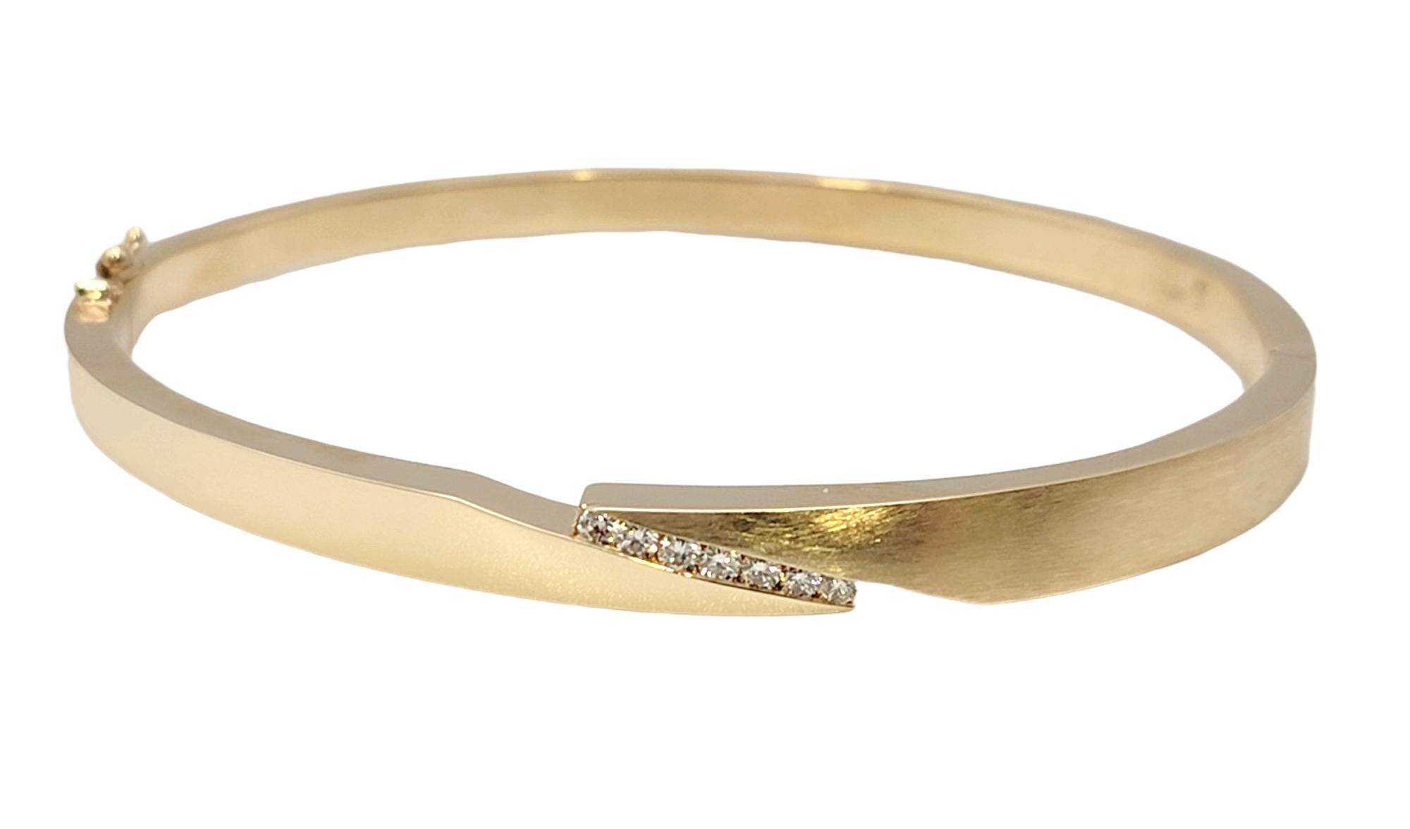 This sleek, contemporary bangle bracelet is effortlessly elegant and absolutely gorgeous. Featuring both polished and brushed yellow gold and a single row of diamonds at the center, this modern beauty is simple enough for everyday wear, yet special