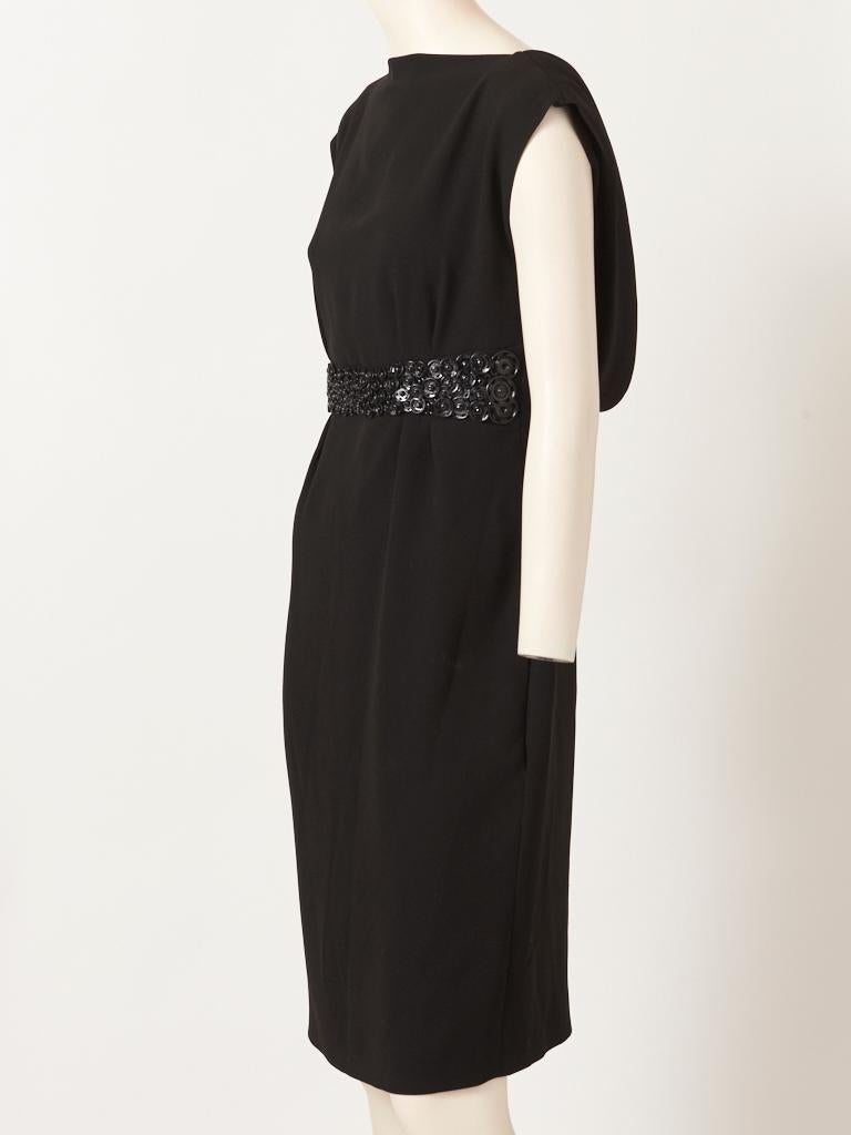 Jean Paul Gaultier, schwarzes, tailliertes Cocktailkleid aus Crêpe, mit Bateau-Ausschnitt, mit schwarzem, glänzendem 
 übergroße, metallene Druckknöpfe am Kleid, die die Taille verschönern. Das Kleid hat einen tiefen, offenen Rücken mit Kutte, mit 