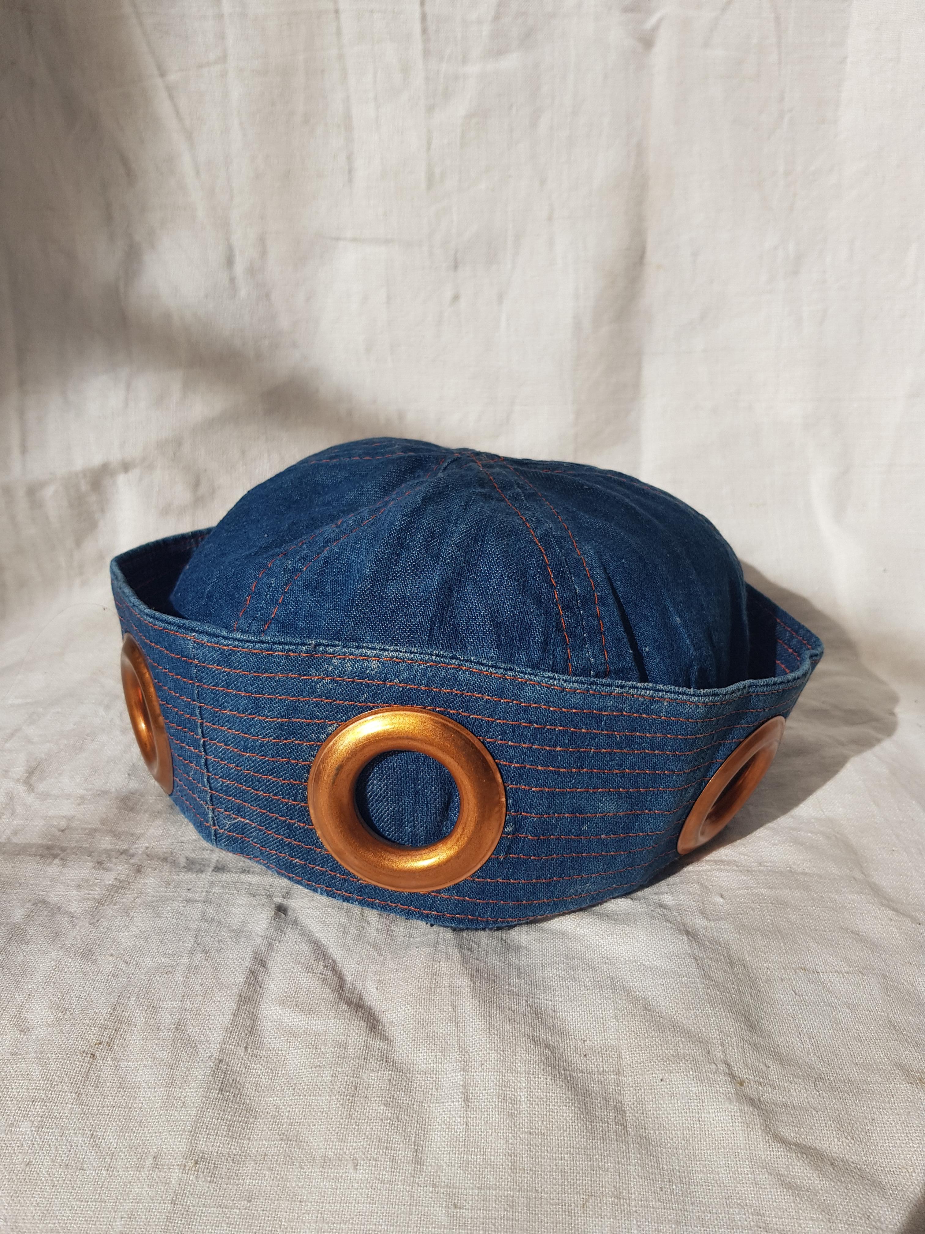 Pièce emblématique de Jean Paul Gaultier Jean's, un chapeau de marin classique et rare en jean provenant directement des années 90.

-Denim
-Circa 1985/1995
-Bagues cuivre métallique
-JPGL'étiquette de Jean
-Taille U, convient jusqu'à la