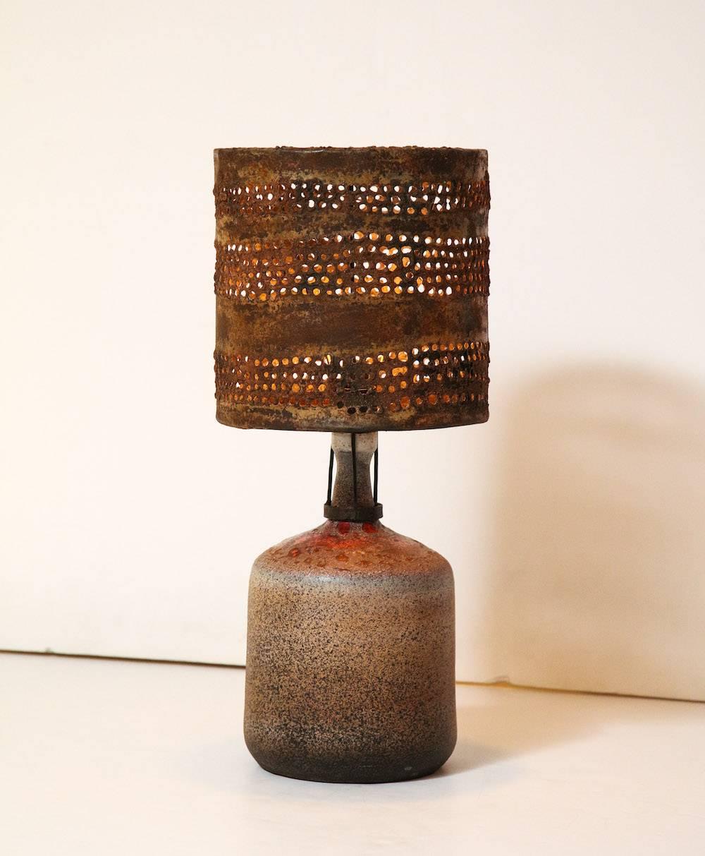 Brutalist table lamp by Gavino Tilocca.
Unique studio-built ceramic lamp with bubble glazes in sand tones with spots of orange. Custom metal shade with cut-outs, and eroded surface. An incredible example of Tilocca's ceramic and metal work.
