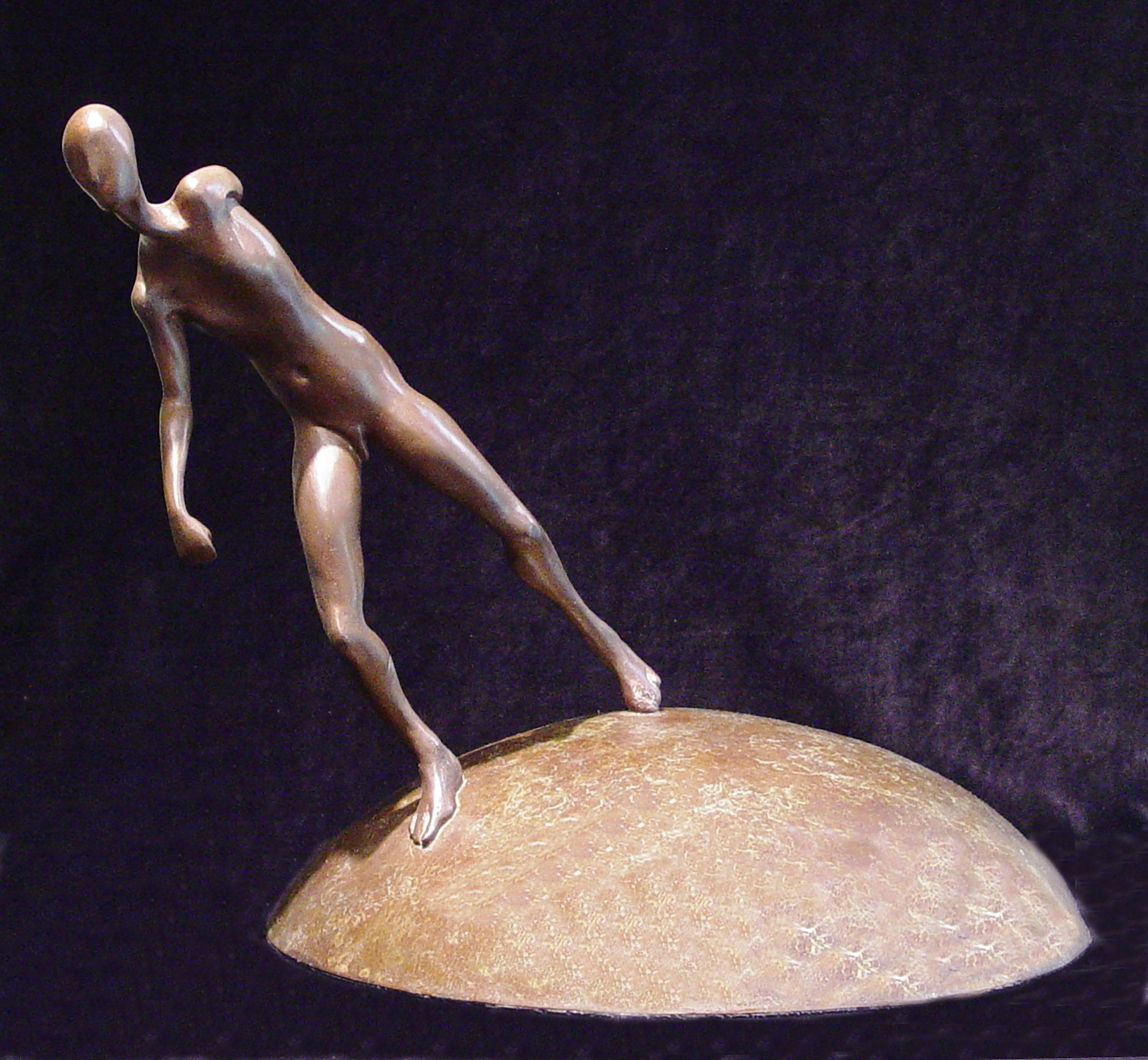 This beautiful bronze sculpture depicts a figure walking on top of a an orb, also in bronze.  The figure, with slightly abstracted features, is walking at a deep angle over the base of the piece. The position of the arms communicate the effort