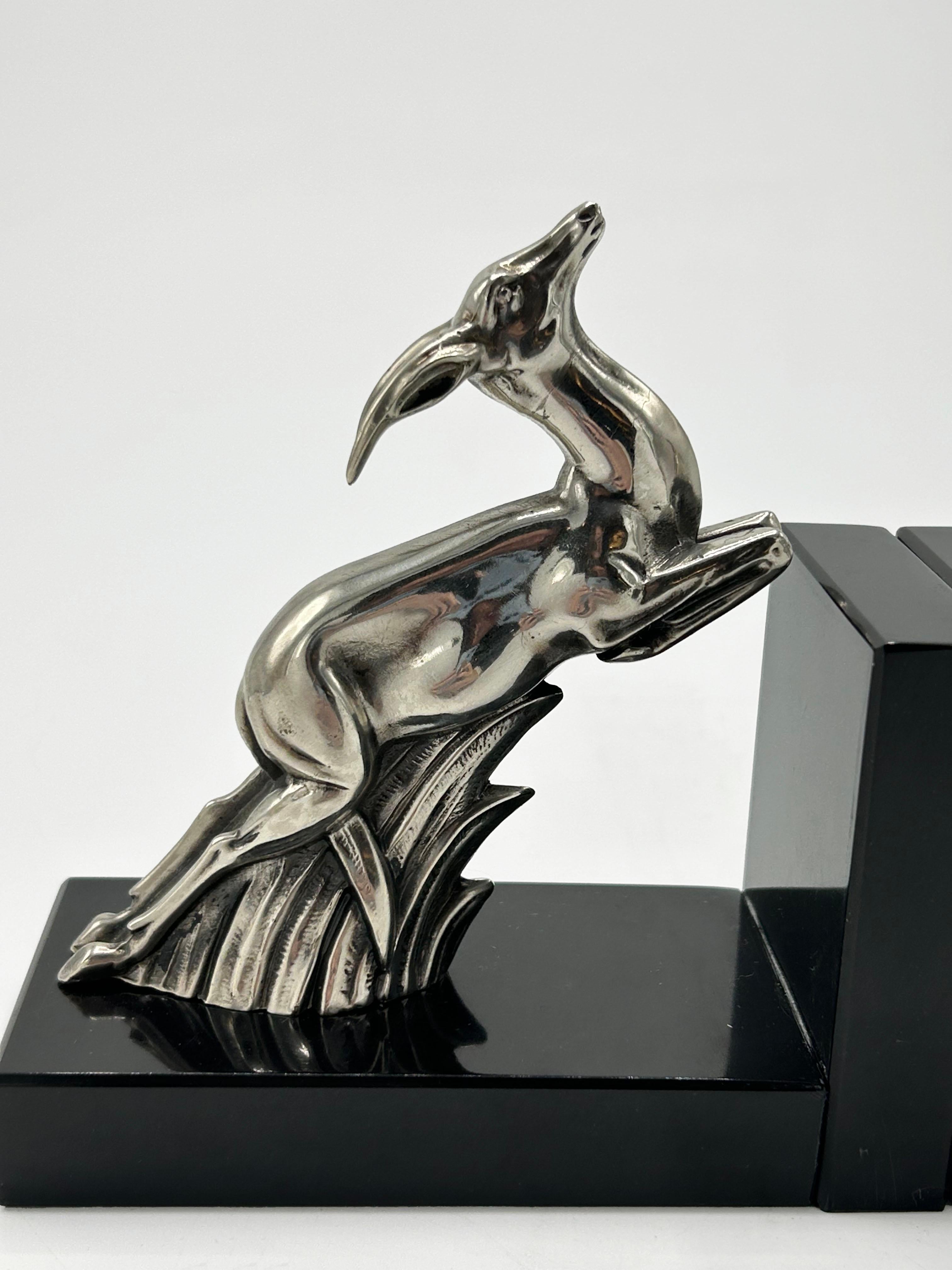 Sujetalibros Art Decó Gacela
Pareja de sujetalibros gacela Art Decó. Las figuras de metal plateado captan el movimiento del animal en una pose dinámica y estilizada característica de la época. Cada figura está montada sobre una base de mármol negro