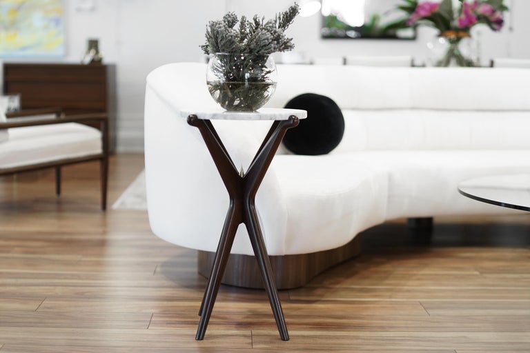Demure curves pair with unexpected sharpness. This solid walnut table has a lightweight aesthetic balanced on strong, hand-sculpted legs. Featuring a grey polished marble top for a natural approach to modernism. A small brass 