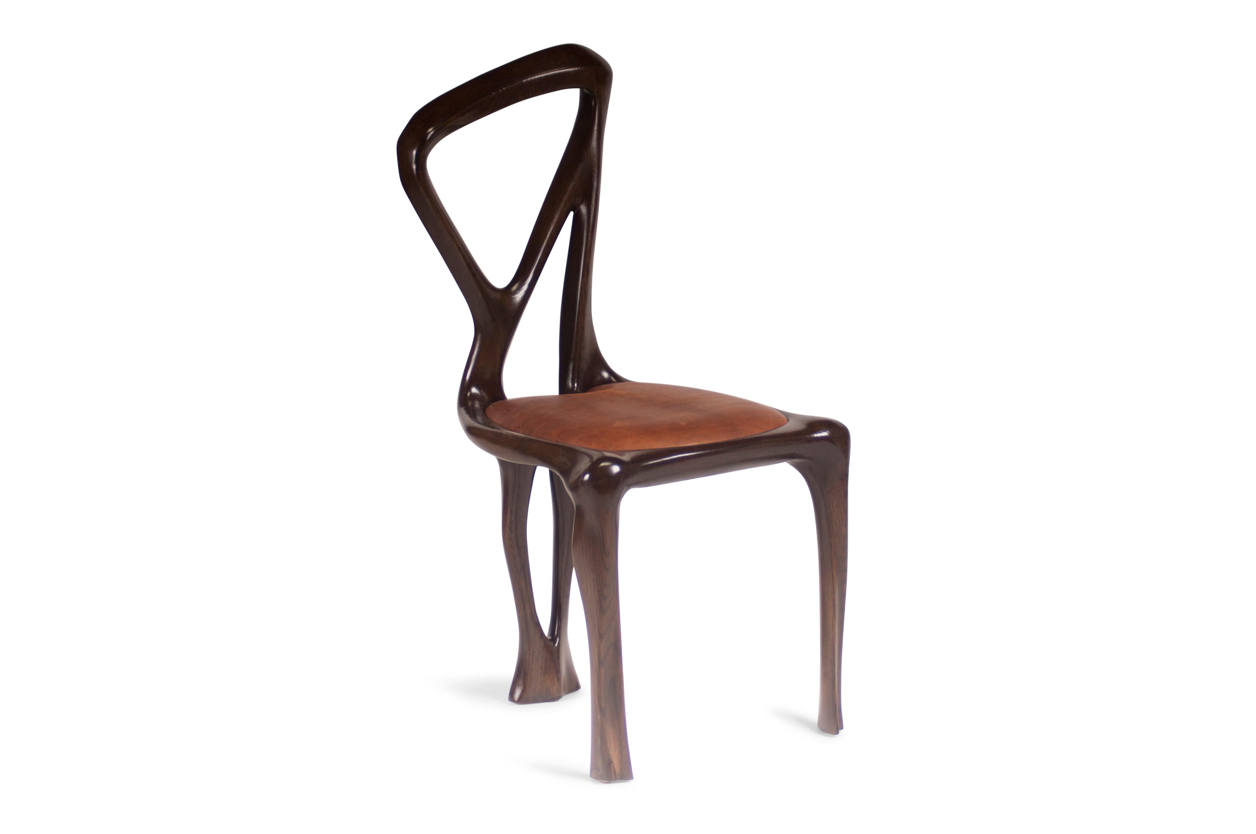 Chaise de salle à manger conçue par Amorph en bois de frêne massif et cuir. Il est teinté noyer foncé.
Dimension : 38