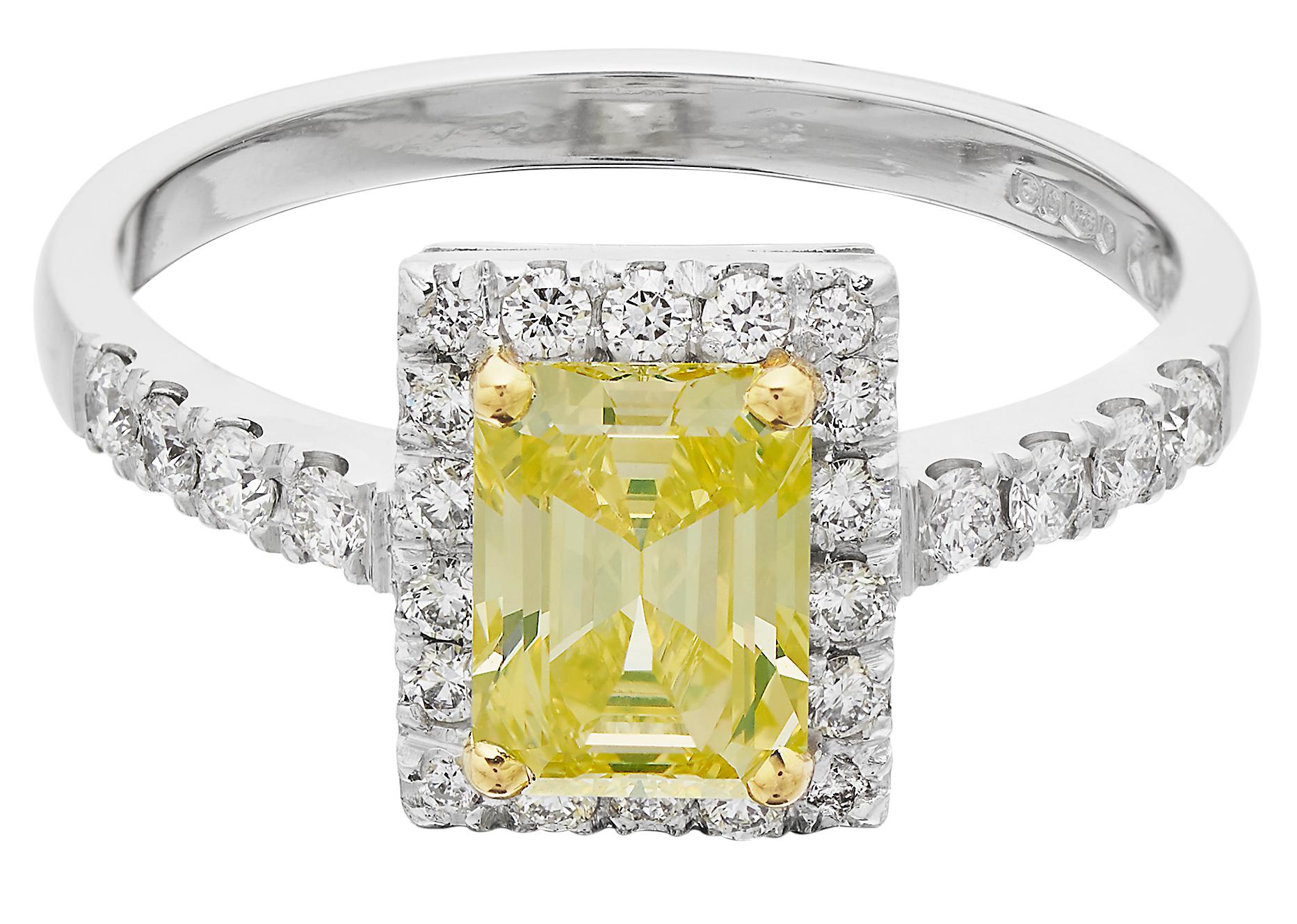 Diamond ring consisting of a stunning rectangular cut fancy intense yellow diamond captured in a yellow gold 4 claws within a frame of round brilliant white diamonds set on a white gold band with diamond shoulder. British hallmarked London platinum