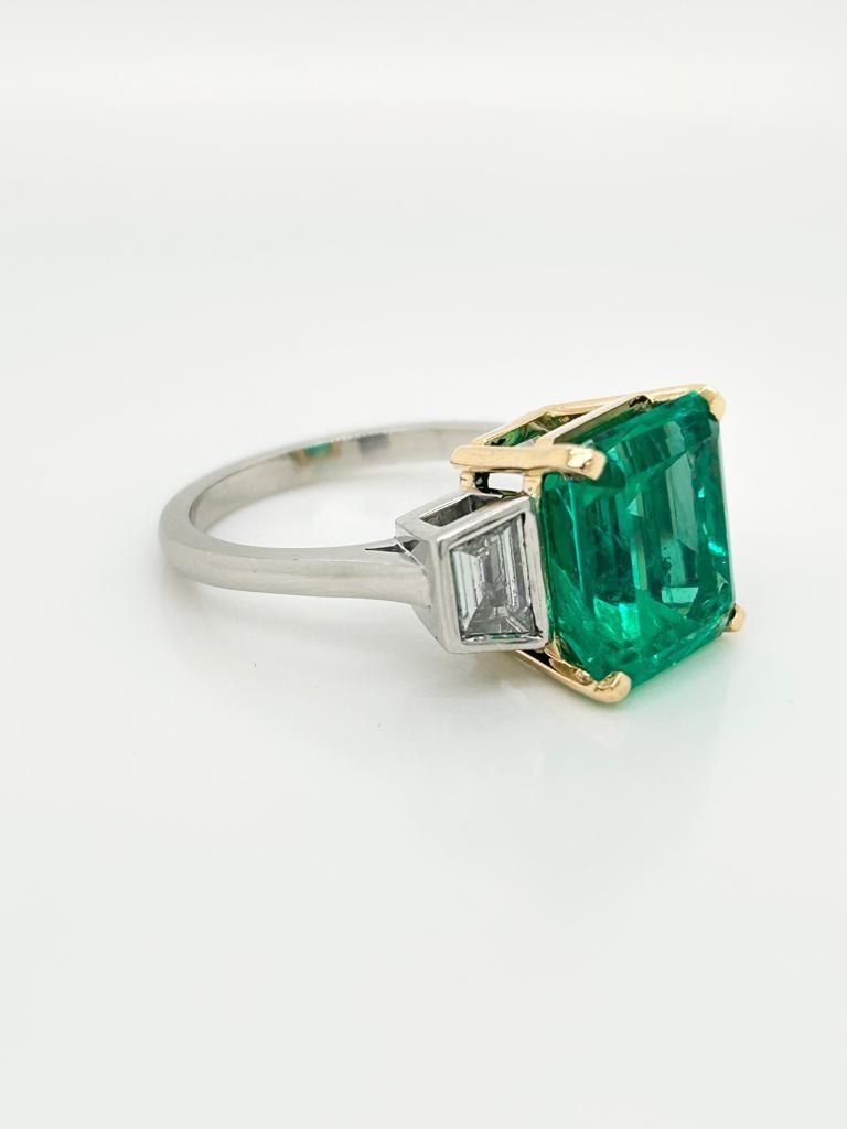 GCS Certified 6.02 Carat Columbian Emerald and Diamond Platinum and 18K Yellow Gold Three-Stone Ring.

This showstopper features an incredible 6.02 carat Colombian Emerald at its centre. On either side of it, in a rubover setting are scintillating