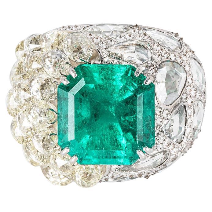 An exceptional Columbian emerald and diamond dress ring. The ring is set to the centre with a square octagonal cut natural Columbian emerald weighing approximately 15.60ct, displaying a medium vivid blue green hue. The exquisite ring features 29