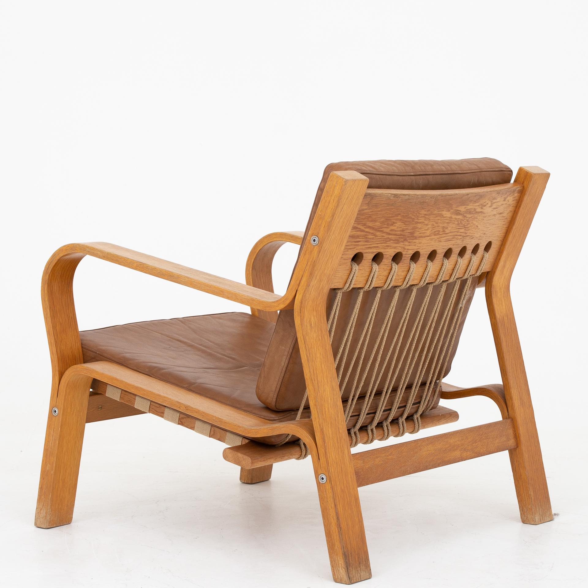 GE 671 - Easy chair in oak and flag halyard with cushions in brown leather. Maker GETAMA.