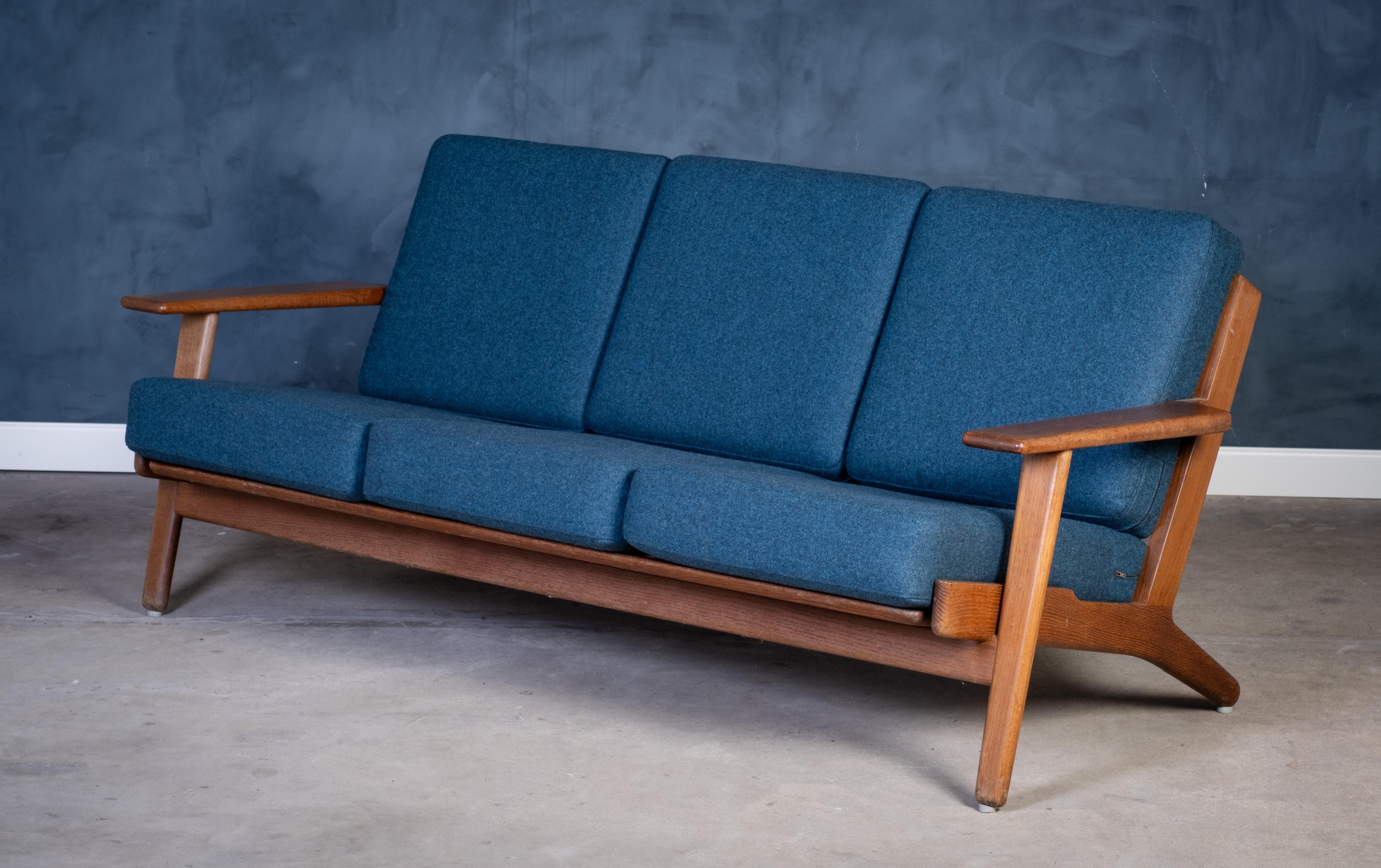 Das ikonische Dreisitzer-Sofa GE290 wurde von Hans J. Wegner entworfen und in den 1960er Jahren von Getama in Dänemark hergestellt. Das aus massiver Eiche gefertigte Möbelstück mit dem für Wegner charakteristischen abgewinkelten Rahmen und den