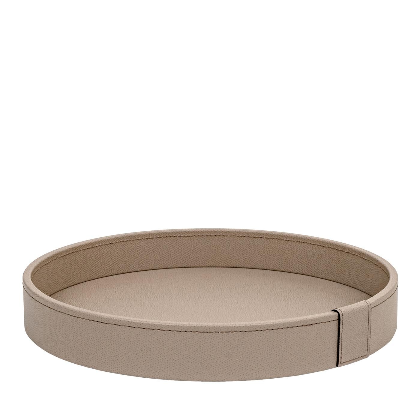 Esta elegante bandeja está fabricada con una estructura de madera elegantemente tapizada en piel beige protegida en la parte inferior con un material antideslizante. La forma redonda, el color y la piel texturizada confieren a esta pieza un encanto