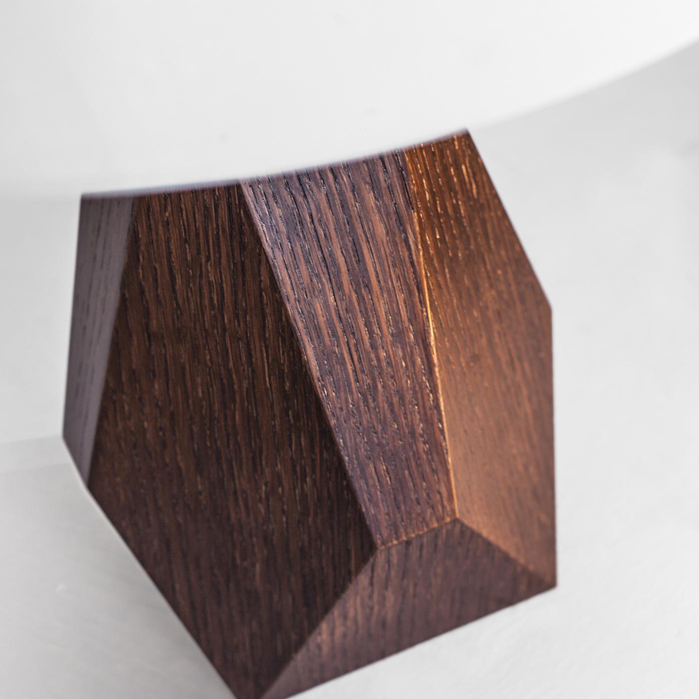 Gea table lamp has an oak structure with shellac finishing, while the metallic parts are in polished brass; the lampshade is in textile. The structure is also available in maple with polished black finishing. Its particular shape makes this lamp a