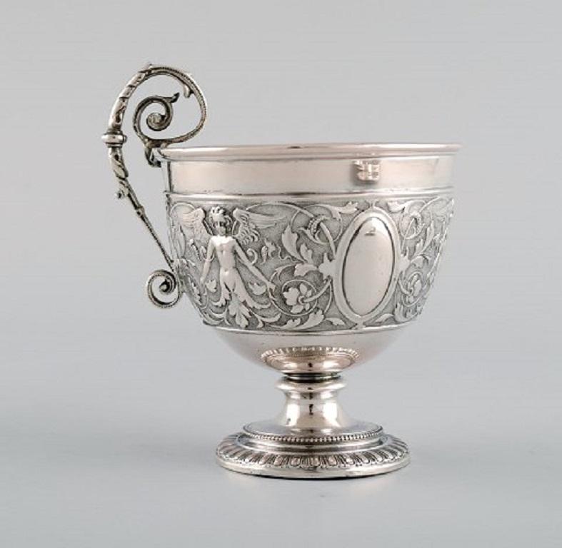 Gebrüder Friedländer, Berlin. Antique coffee cup/goblet with saucer in silver with classicist motifs. 
Early 20th century.
The cup measures: 10 x 7.5 cm.
The saucer measures: 13 cm.
Stamped.
In excellent condition.