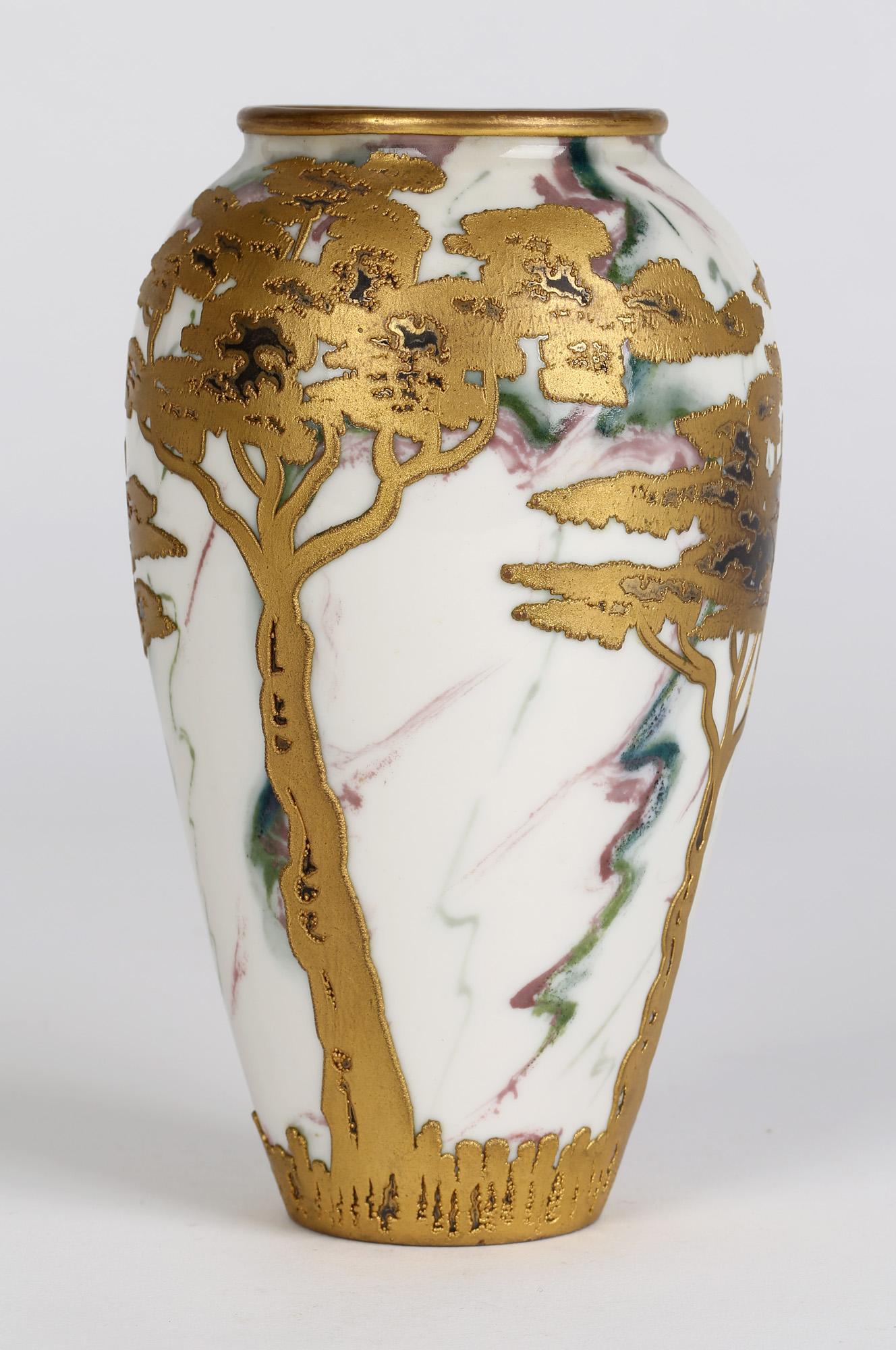 A very stylish German Art Nouveau porcelain vase applied with gilded stylized trees by Gebrüder Heubach and dating from the latter 19th or early 20th century and pre 1906. This finely made vase has a marbled body with green and red veining on a