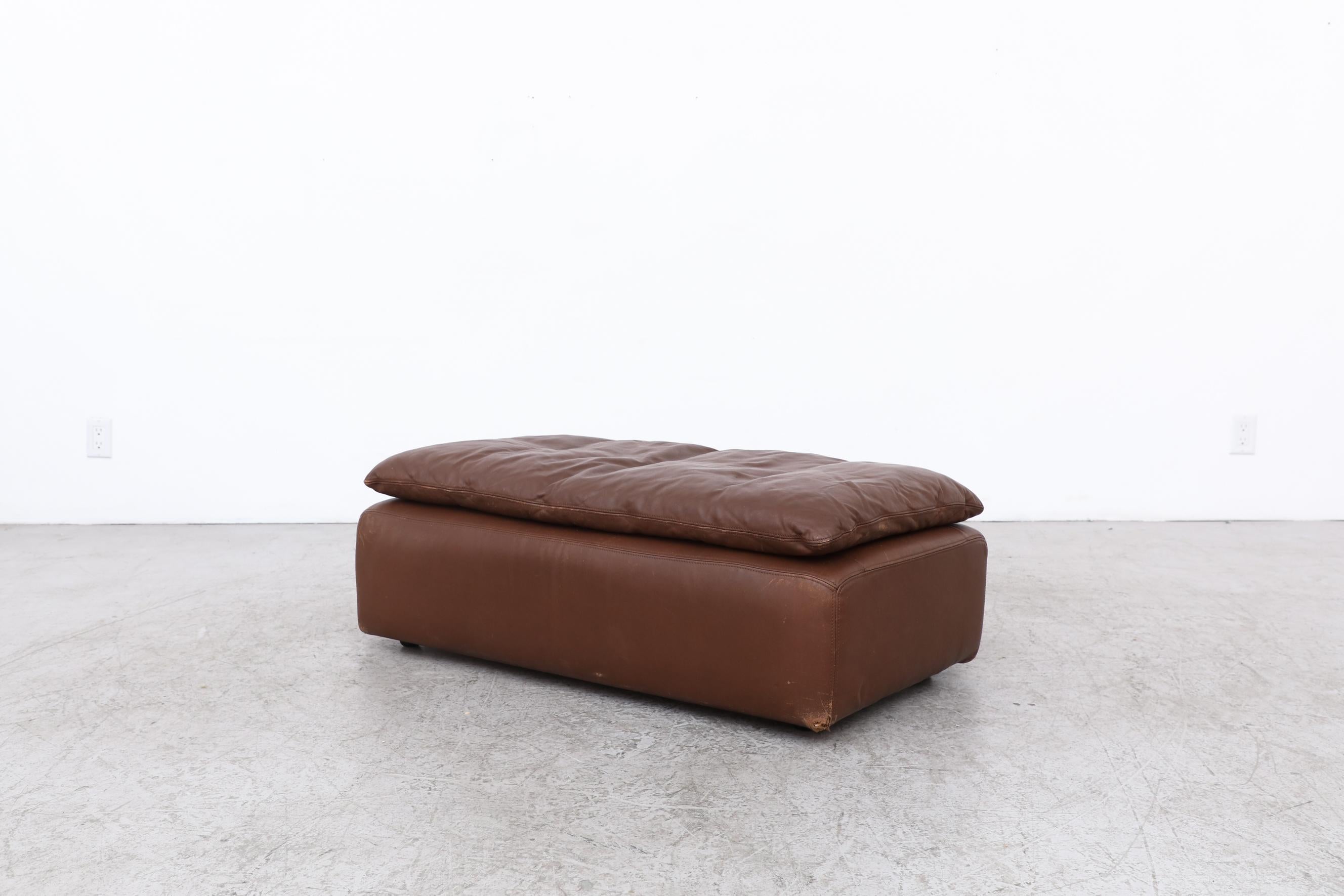 Extra wide Gelderland chocolate brown leather ottoman with a top cushion. In original condition with visible wear and scratching as well as a small tear on the bottom corner. Wear is consistent with its age and use.