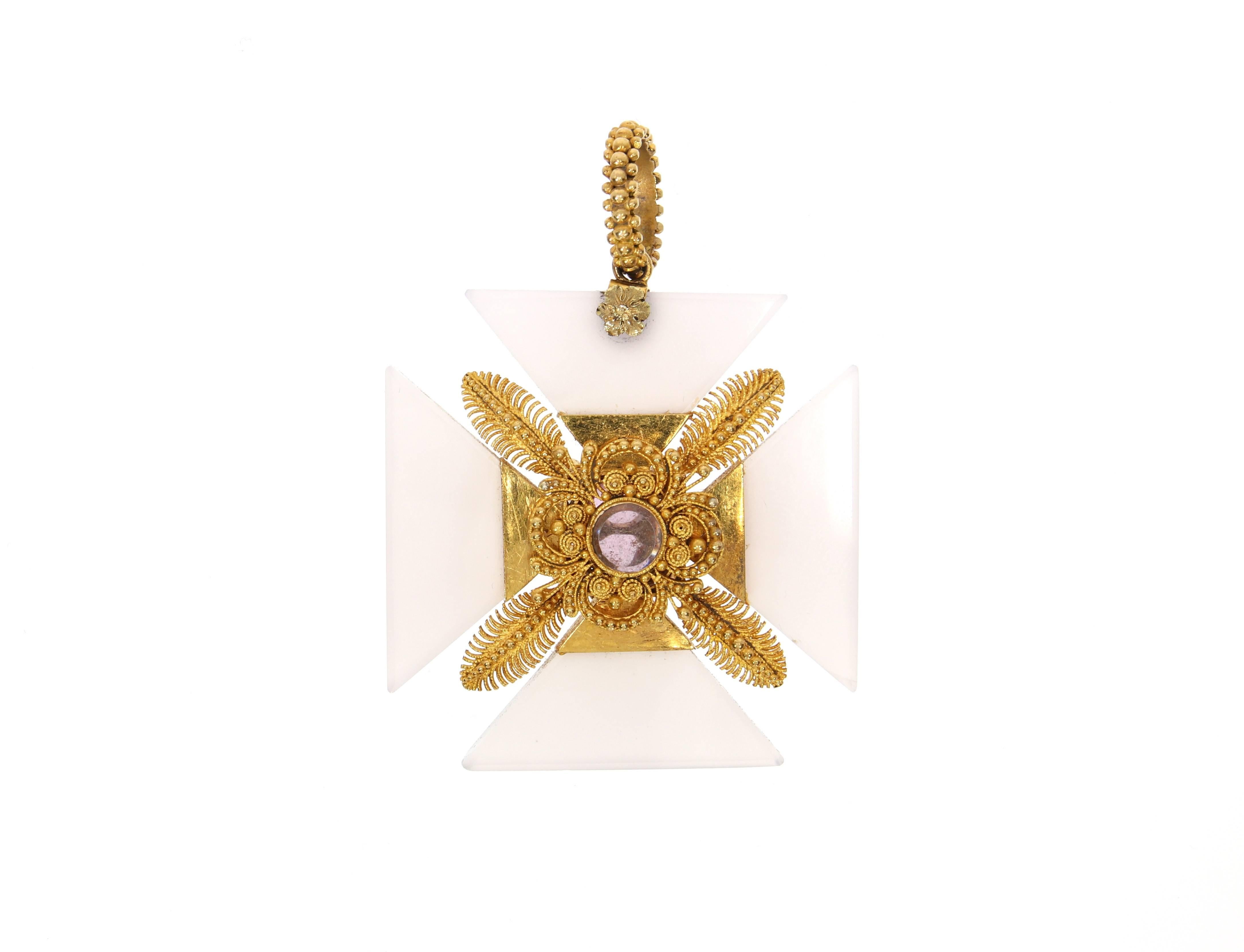 An enchanting Maltese cross pendant from the early 19th century. It is made from carved milky chalcedony. To the center, the cross is filigrain granulated in 14 Karats/ 18 Karats gold plated yellow gold- on both sides. A pink topaz, surrounded by 4