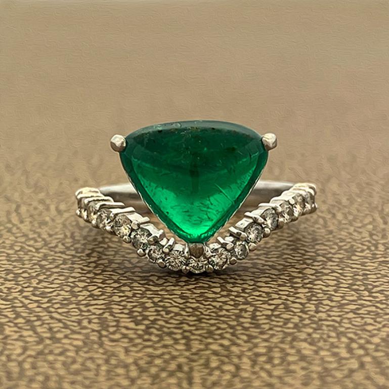 A shapely ring featuring a 3.94 carat gem Columbian Emerald certified by the AGL. The smooth cabochon trilliant cut emerald is set in a martini prong setting positioned atop a curved band. The platinum band is adorned with 0.43 carats of round cut