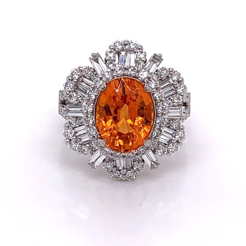 A special garnet with a vivid orange color and near flawless crystal This oval shaped stone weighs in at 5.14 carats and is truly a top-quality example of its type. It is accented by 1.83 carats of round and baguette cut diamonds set in a sunburst
