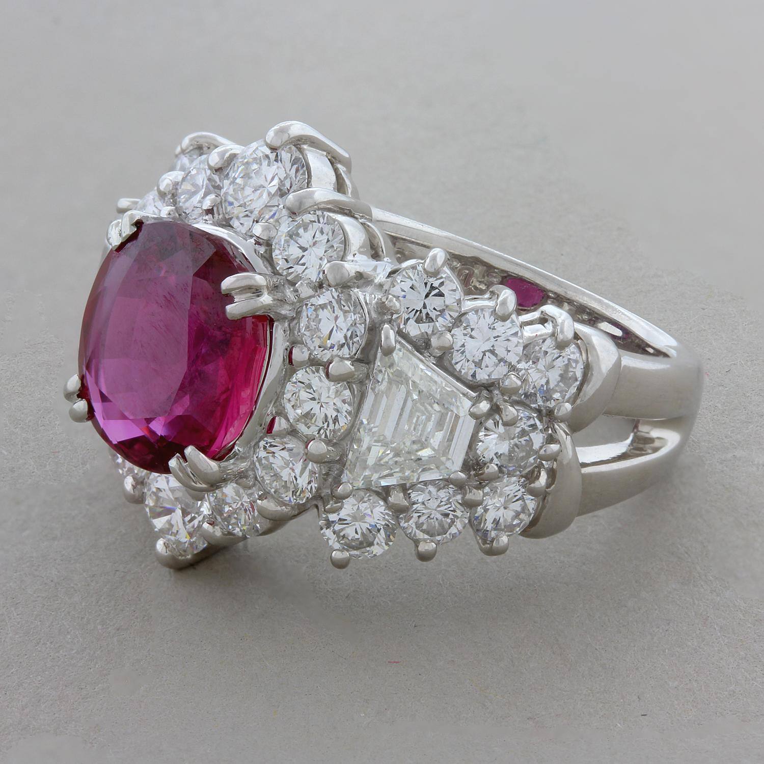 A royal ring featuring an intense 3.64 carats red ruby in a double prong setting. The immaculate precious oval shaped ruby is surrounded by 3.35 carats of round and trapezoid cut VS quality colorless diamonds. This fiercely sophisticated ring is