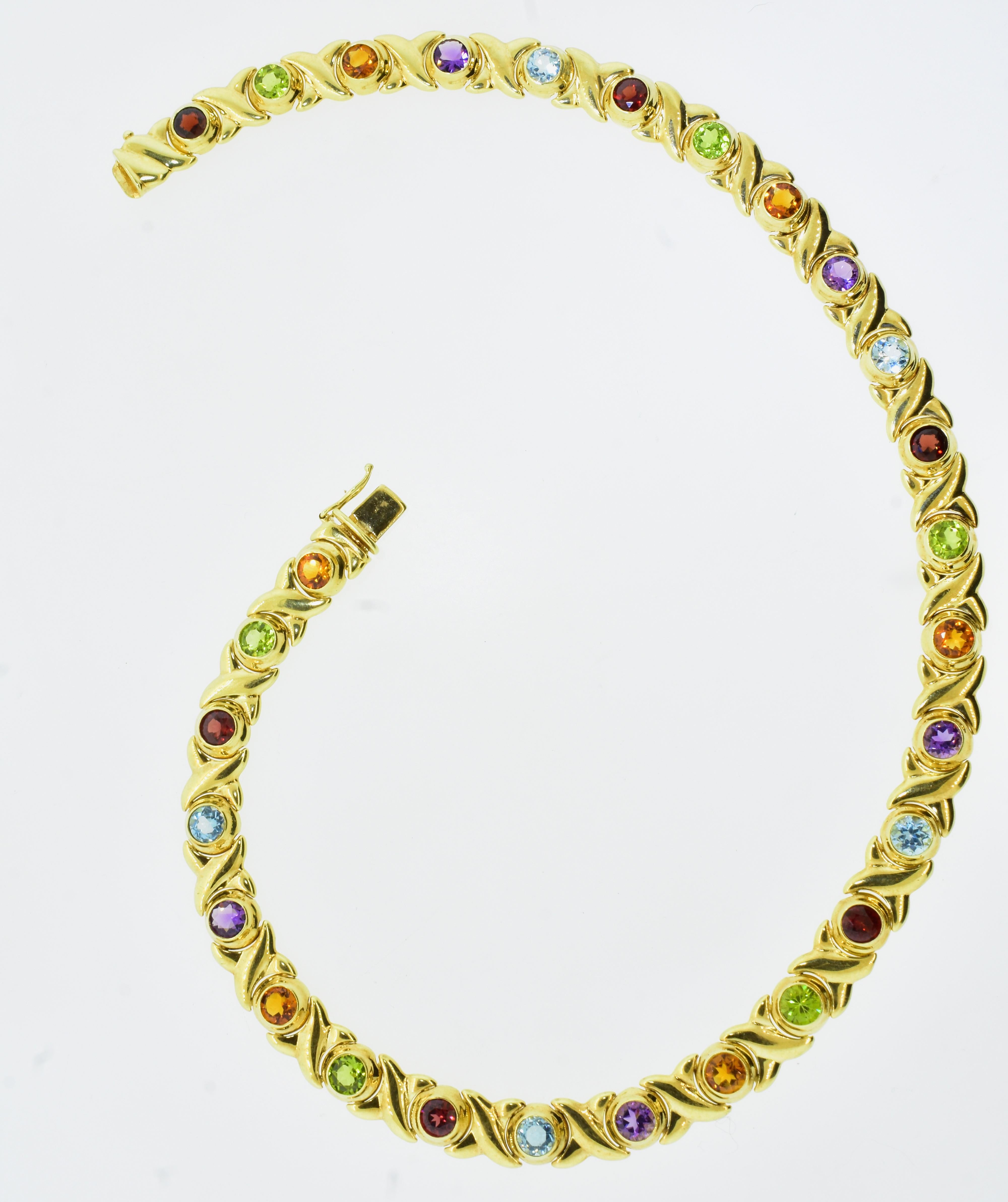 Fine multi-color natural gems are bezel set in a fine yellow gold necklace.  The 28 natural bright round brilliant cut stones  - 5 amethyst, 6 peridot, 6 madeira citrine, 6 garnet and 5 blue topaz are all set between yellow gold X motifs.  The