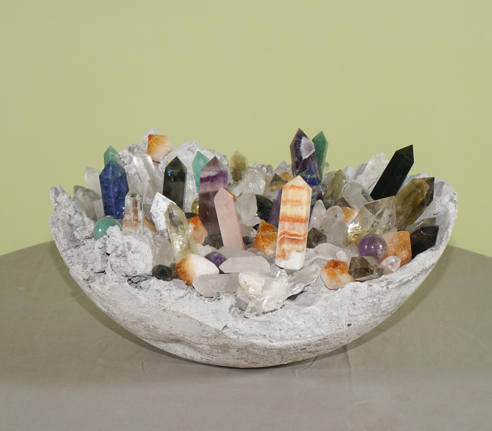 This collection of wands and spheres along with naturally formed crystals are all displayed in a custom-made concrete geode bowl. The stones are of many different varieties such as fluorite, amethyst, citrine, rose quartz, garnet, obsidian,