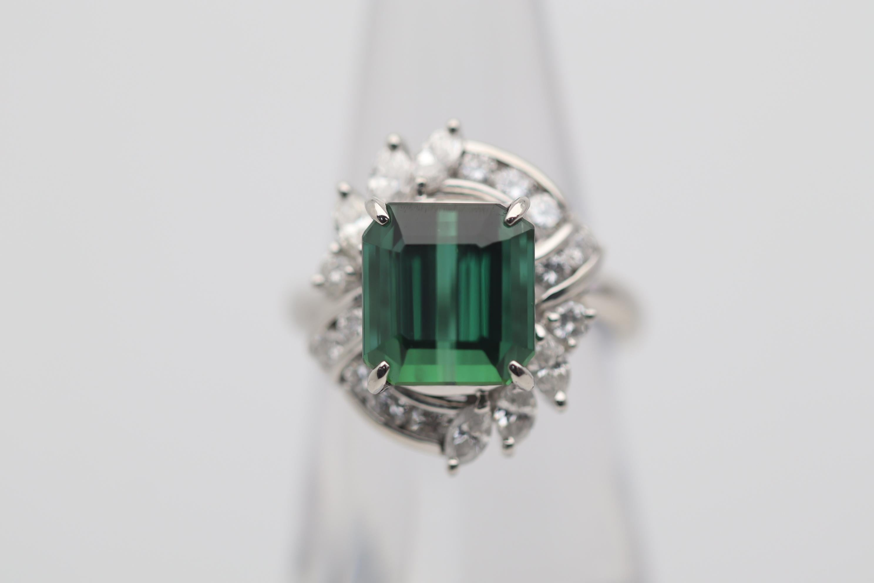 A superb gem tourmaline of exceptional quality. It weighs 5.89 carats and has the most vivid and intense slightly bluish-green color. Rarely do we see tourmaline of this quality. It is complemented by 1.02 carats of round brilliant and