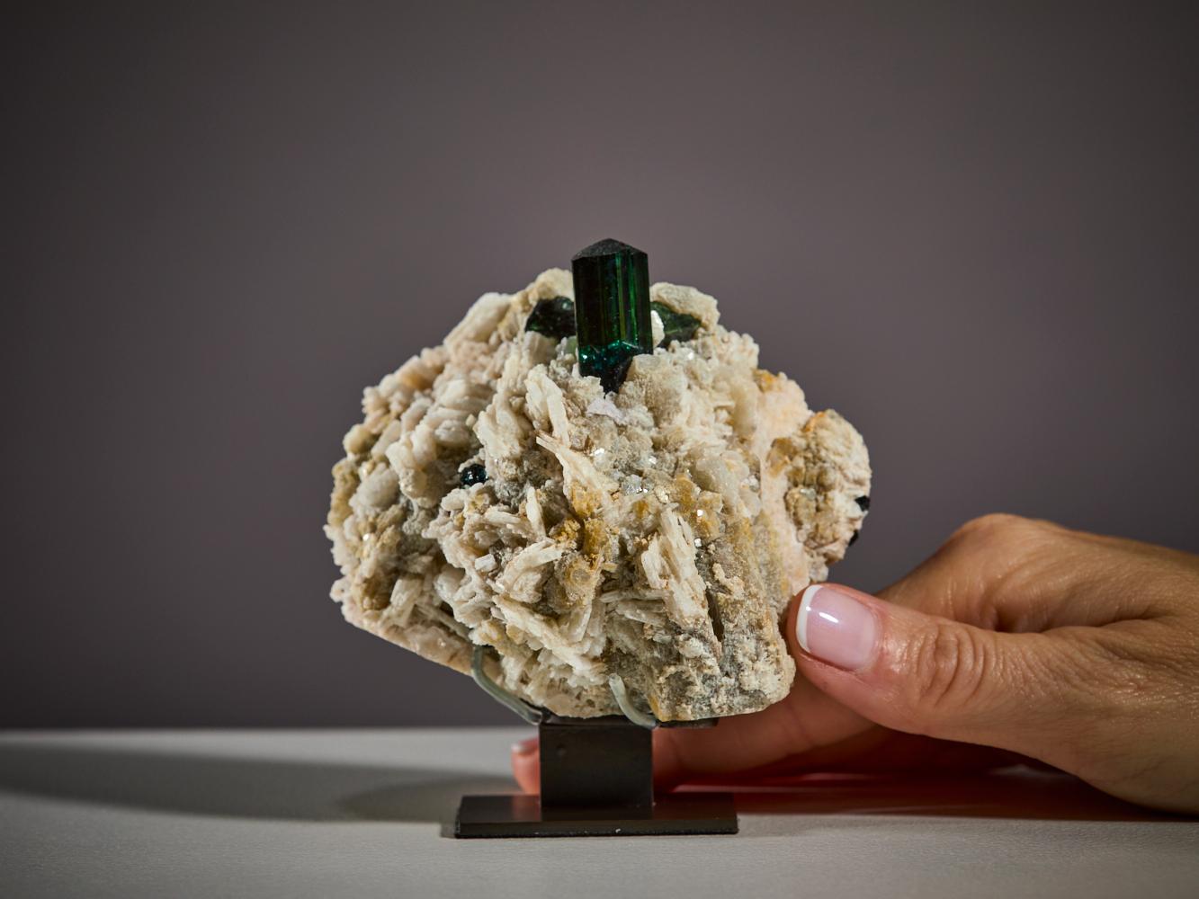 Un'impressionante tormalina verde di qualità gemmologica emerge dalla sua matrice naturale,
formando una composizione perfettamente bilanciata e allo stesso tempo potente
ed elegante.

Proveniente dai rinomati giacimenti del Pakistan, questa