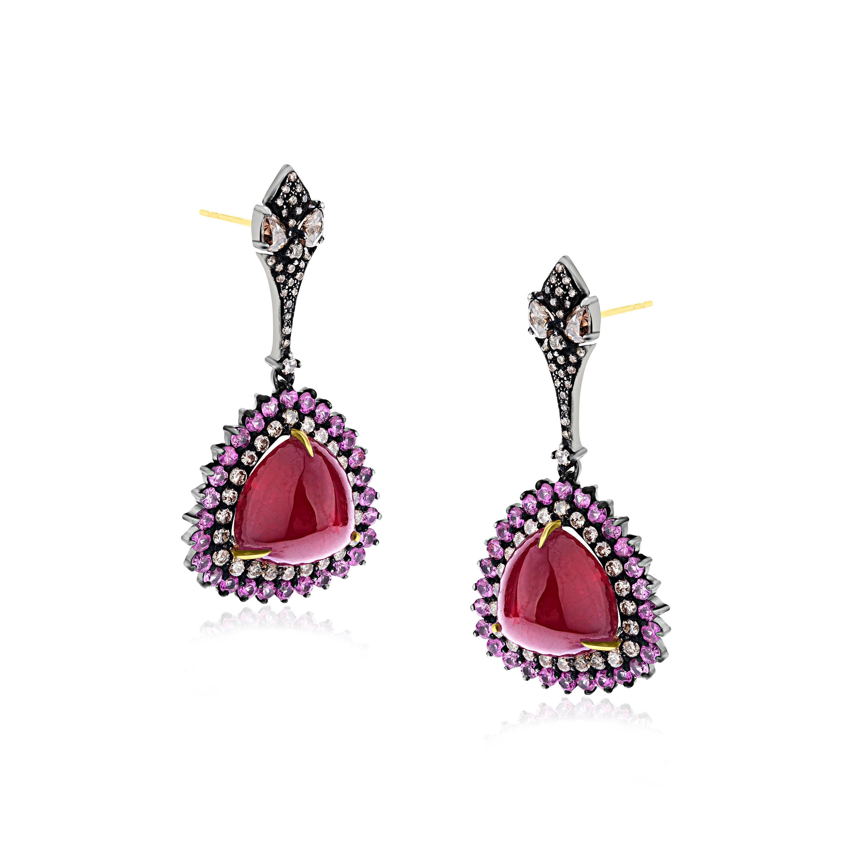 This Gemistry, dazzling earrings of pink hue are manifested on an 18K/925 White & Black Rhodium and Sterling Silver. Trillion cut Ruby drops in diamond and Pink sapphire halos add glamour to this vibrant dangle earring. The colorful pair of